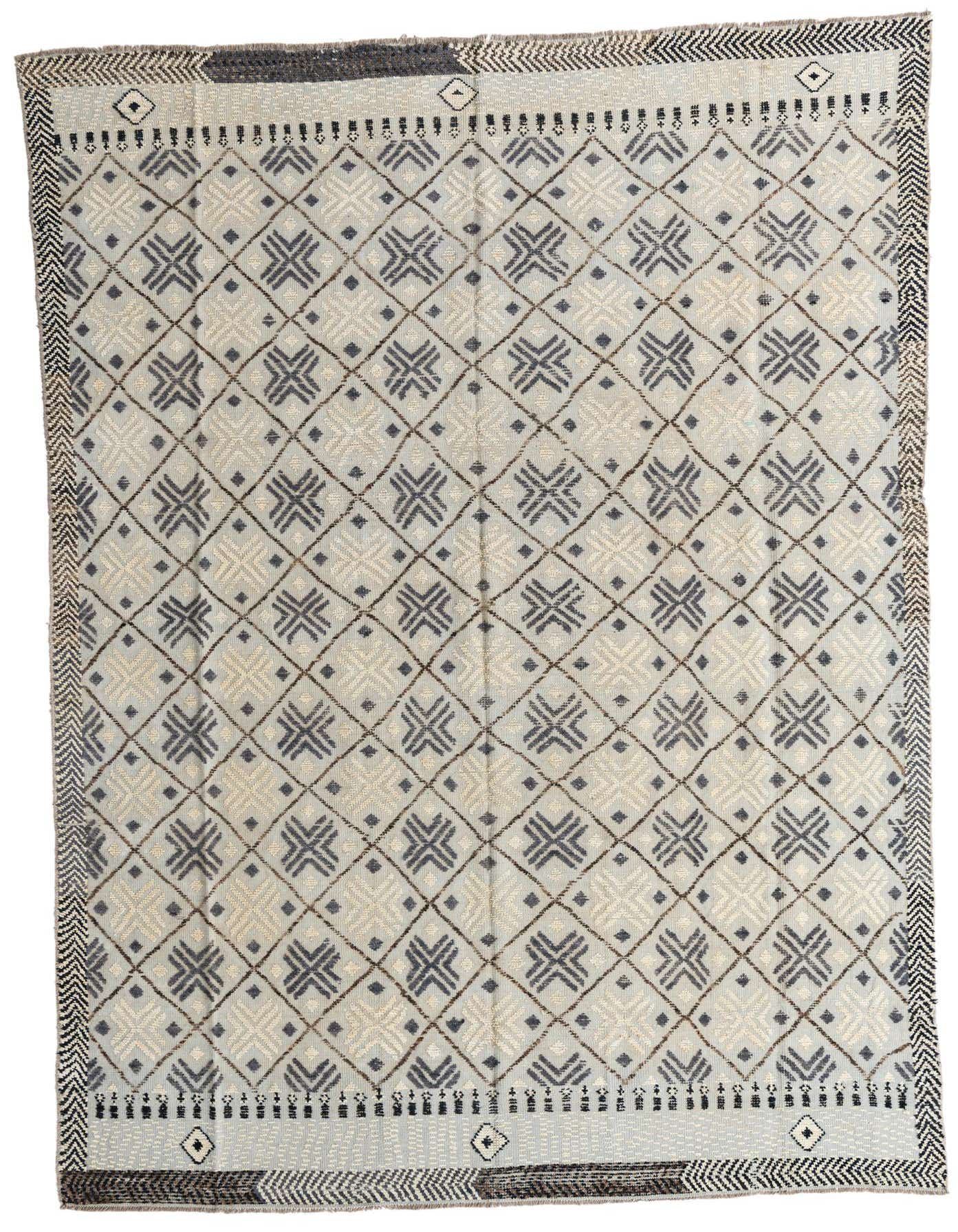 A large 8x12 rectangular gray wool shag rug with a repeating tribal geometric pattern and border.