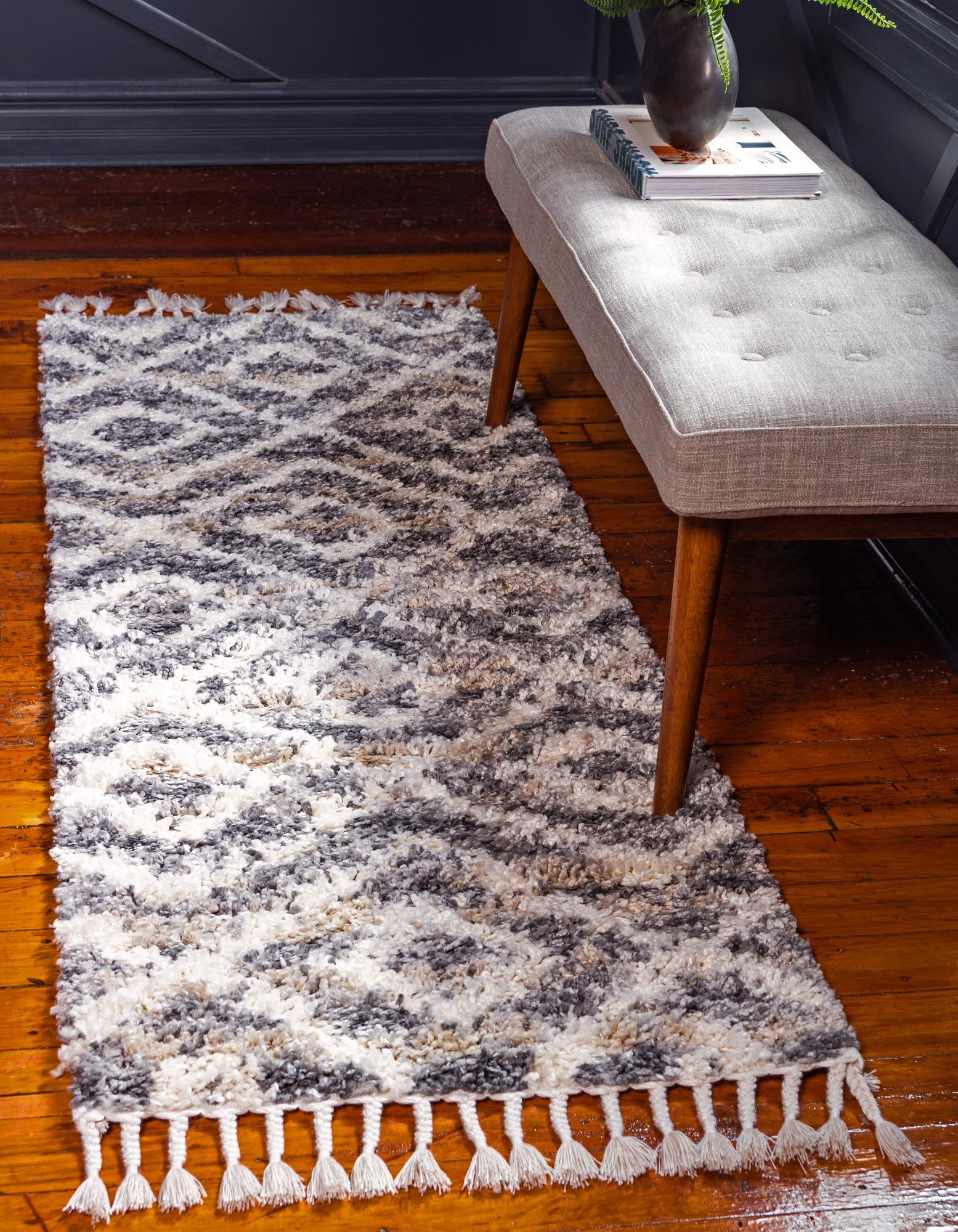 A 6 ft runner rug from the Athena Shag collection, featuring a gray and off-white tribal geometric pattern with tassels, ideal for hallways.