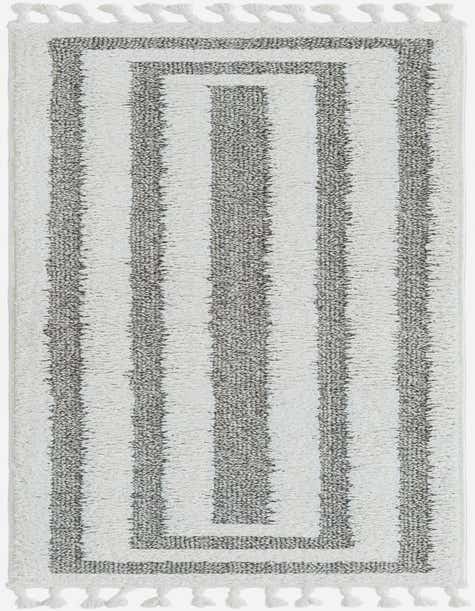 A gray and white striped runner rug with a modern pattern and fringe, perfect for a hallway.