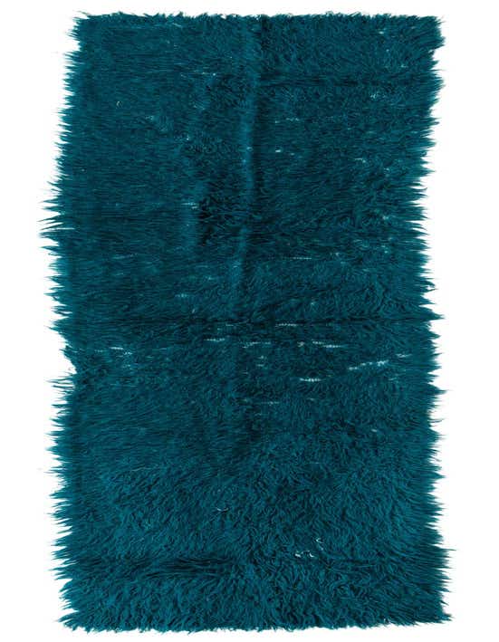 A long, rectangular 11 ft runner rug in a deep teal green shag pile, handmade from wool.
