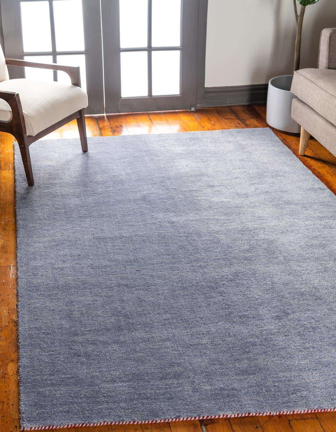 An 8x11 rectangular grey wool rug with a subtle texture, laid on a hardwood floor in a living room setting.