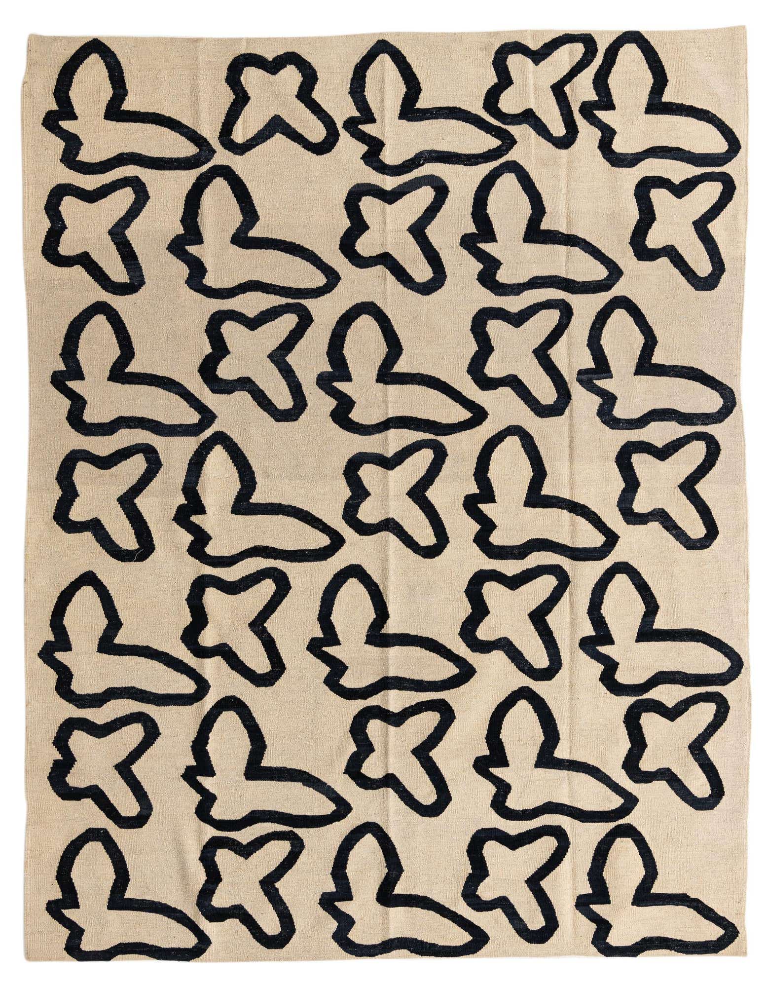 A 6x9 rectangular ivory wool flatweave rug with a repeating abstract black tribal pattern, suitable for a living room.