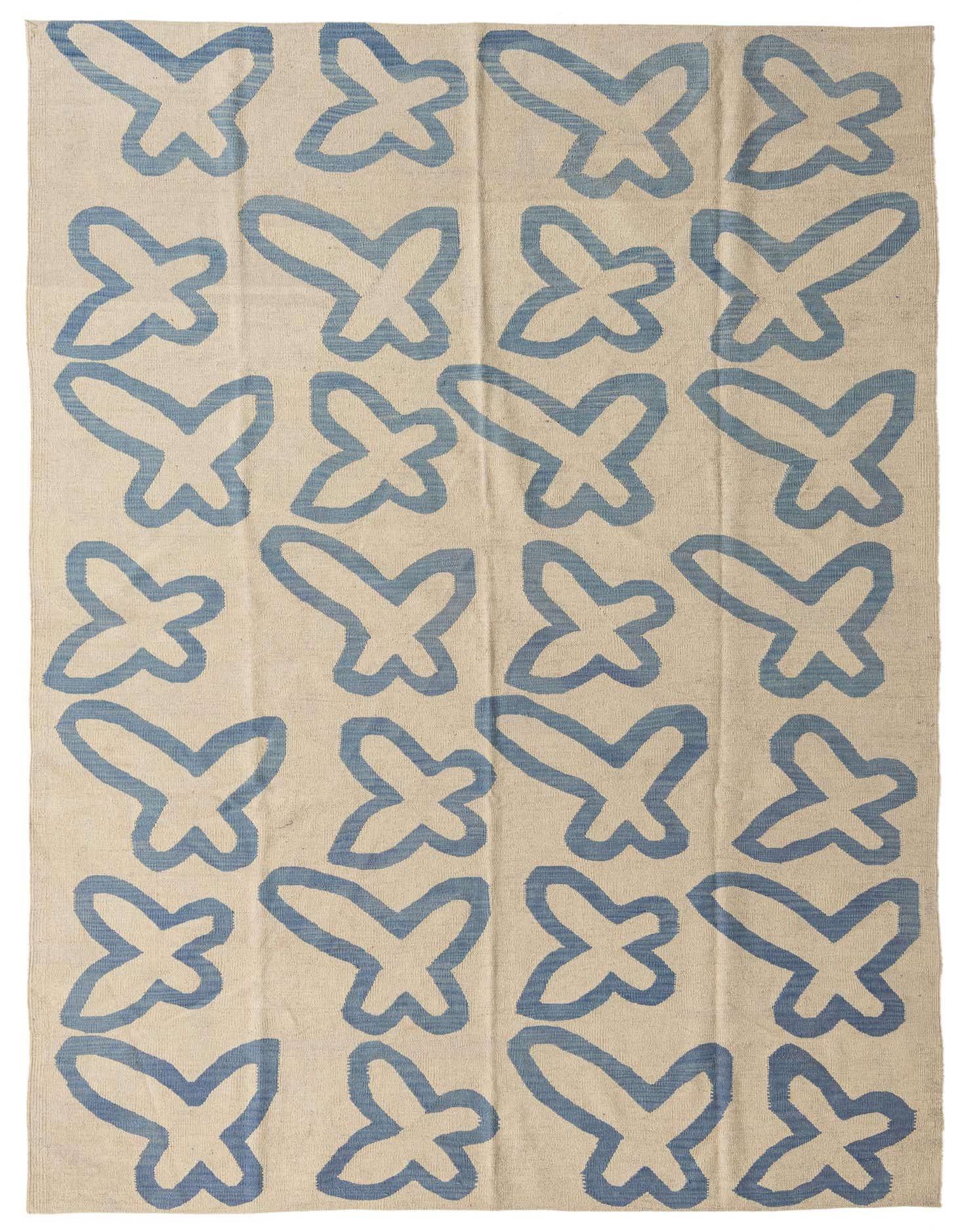 A 6x9 rectangular flatweave rug with a cream background and a repeating pattern of abstract blue butterfly-like shapes.