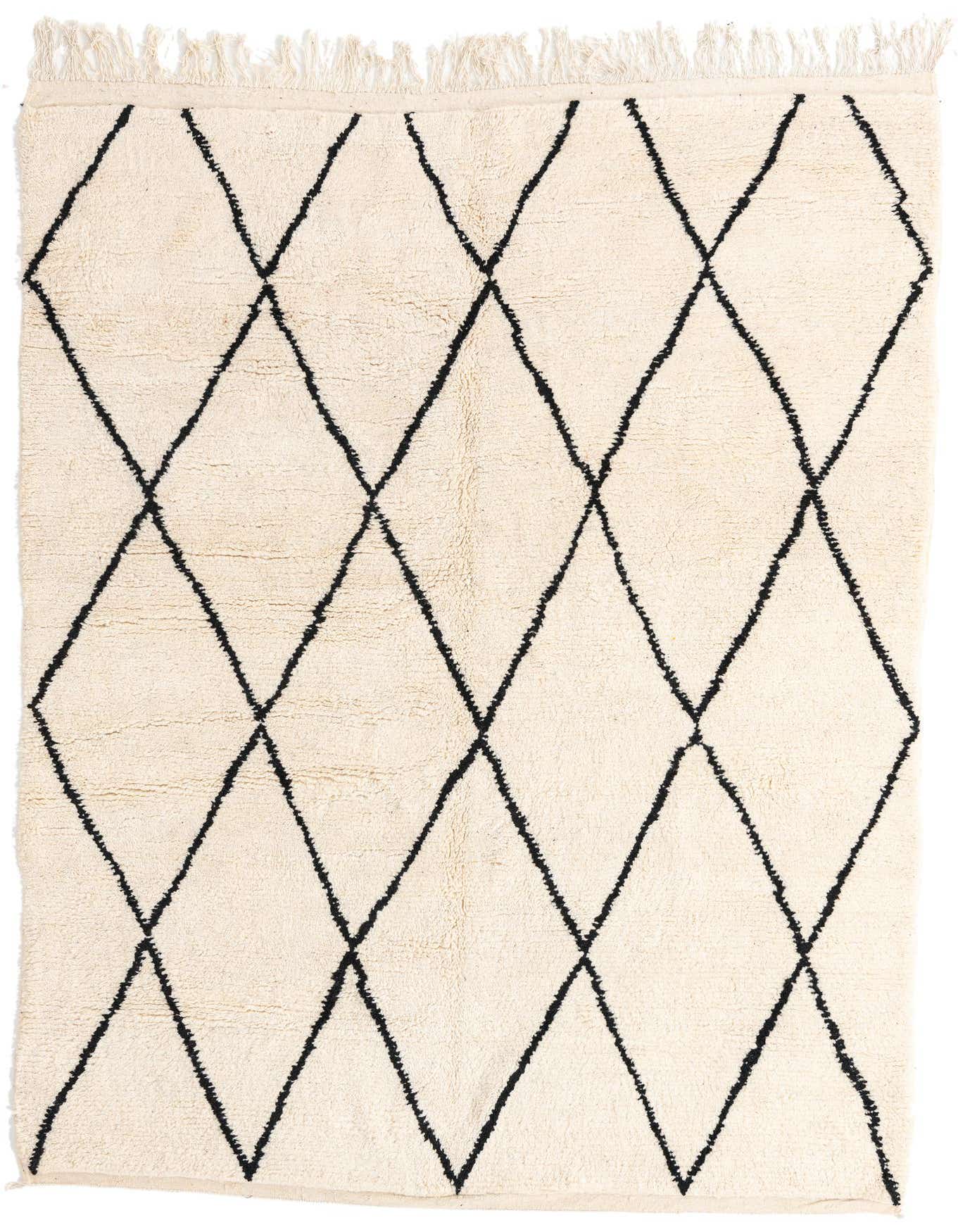 A 7x10 rectangular ivory shag rug with a bold black tribal diamond pattern and fringed edges.