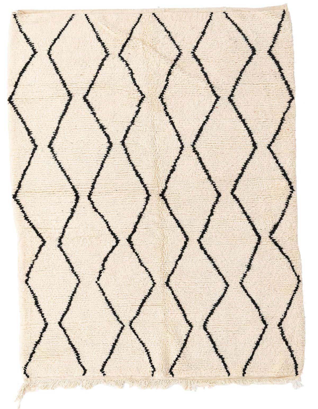 A 5x8 rectangular ivory shag rug with a black tribal diamond pattern and fringed edges, suitable for a living room.