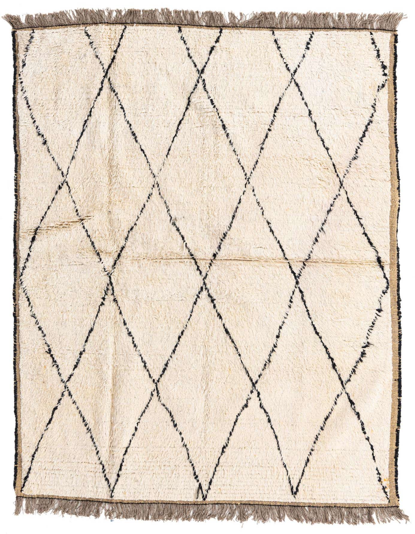 A 5x8 rectangular ivory shag rug with a bold black tribal diamond pattern and fringed edges, ideal for a living room.