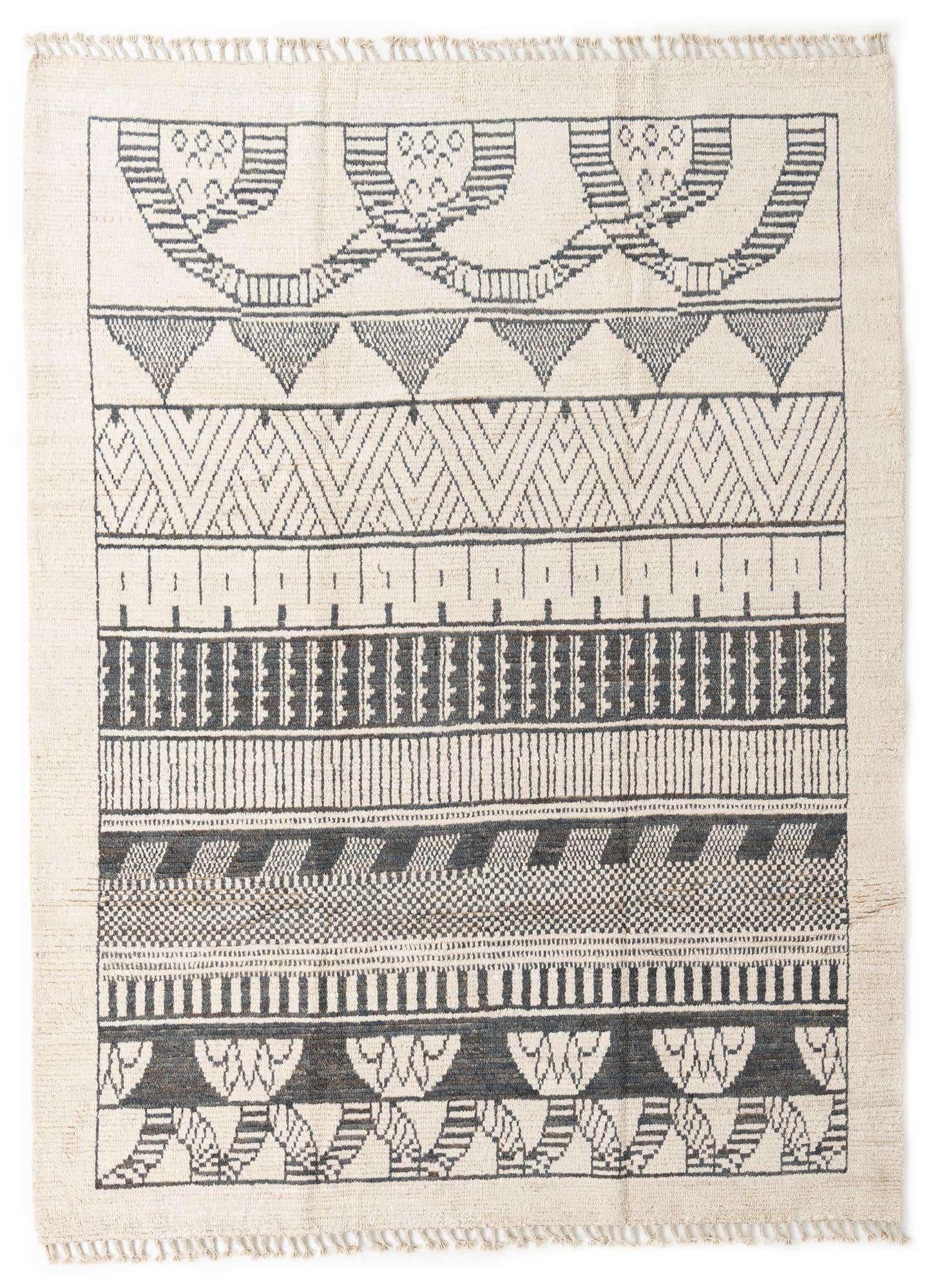 An 8x10 rectangular ivory and black tribal wool shag rug with varied geometric patterns and fringed edges.