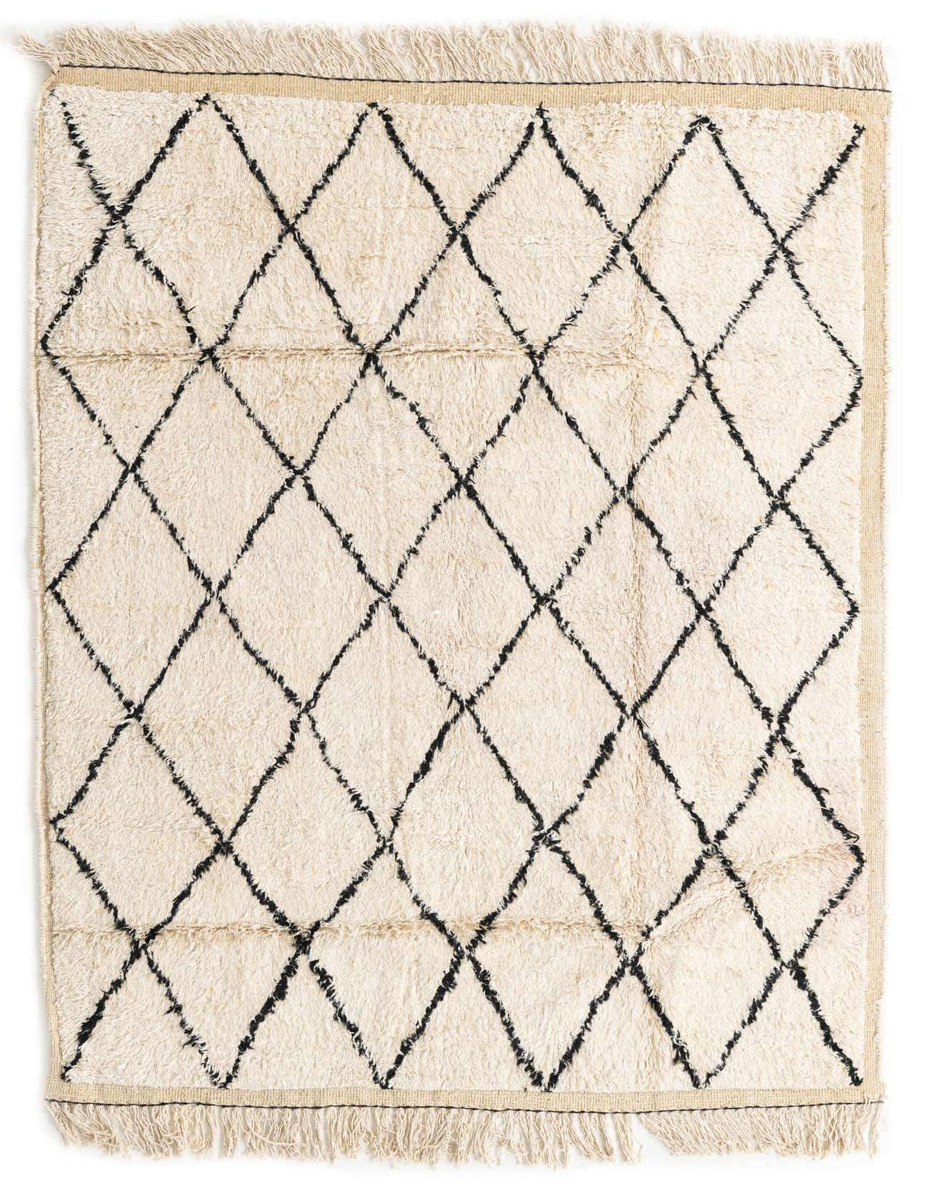 A 5x8 rectangular ivory shag rug with a black tribal diamond pattern and fringe, suitable for a living room.