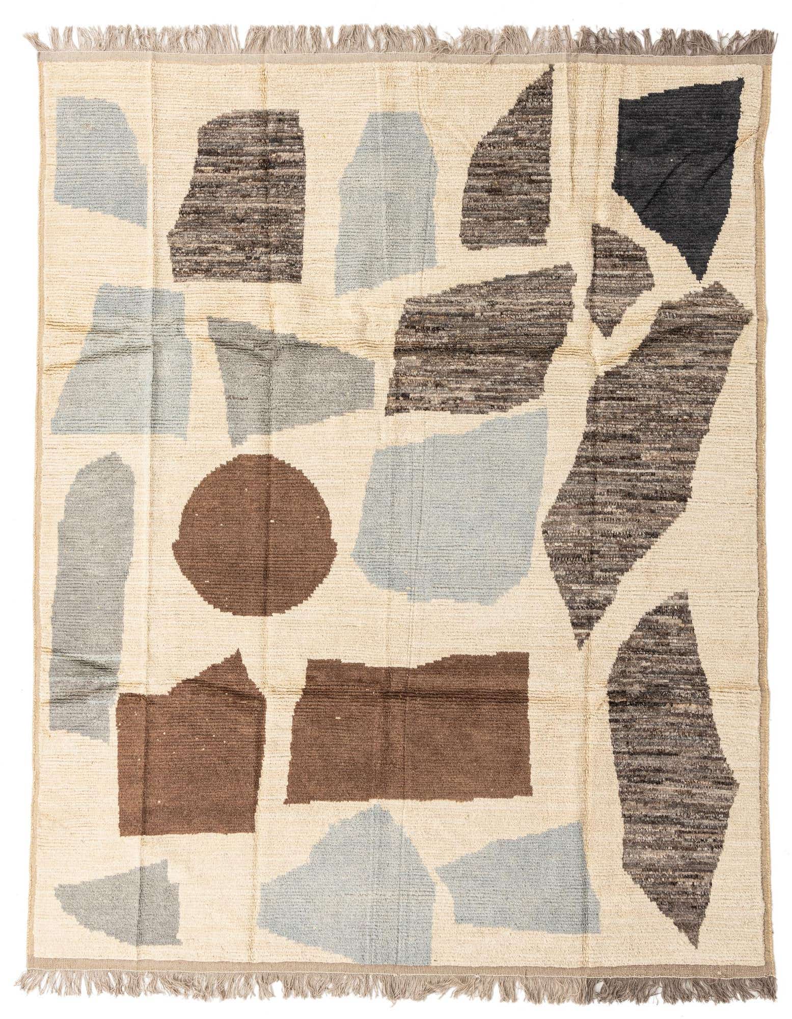An 8x10 rectangular ivory shag rug with abstract shapes in light blue, brown, and charcoal, featuring fringe.