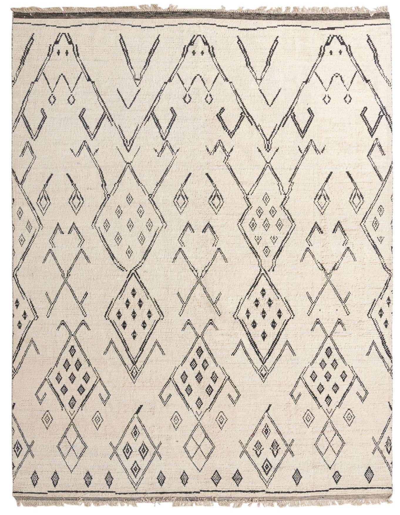 A 10x14 rectangular ivory wool shag rug with a bold black tribal geometric pattern, featuring diamonds and zigzags.