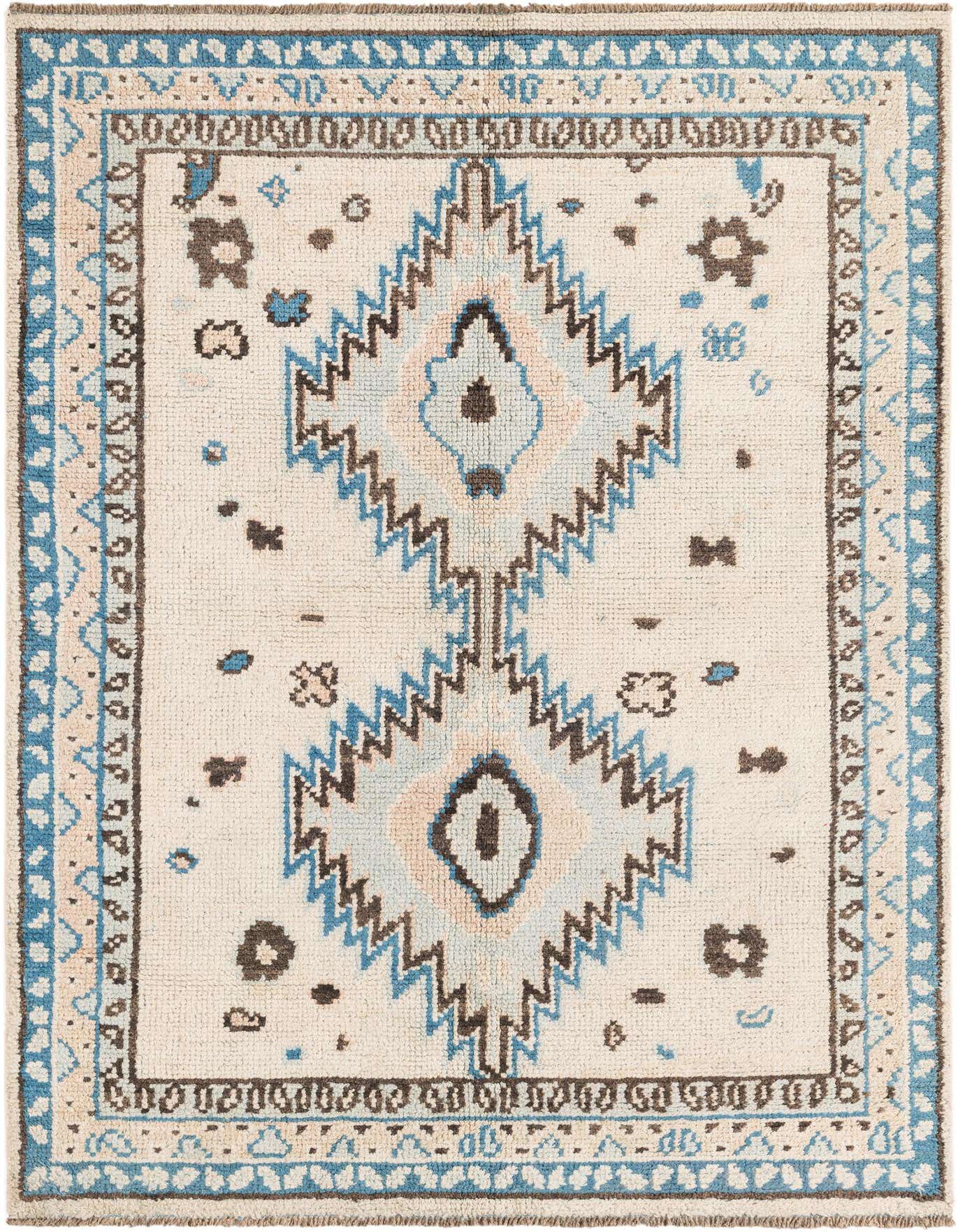 A 5x8 rectangular ivory shag rug with a central blue and brown tribal medallion pattern, ideal for a living room.