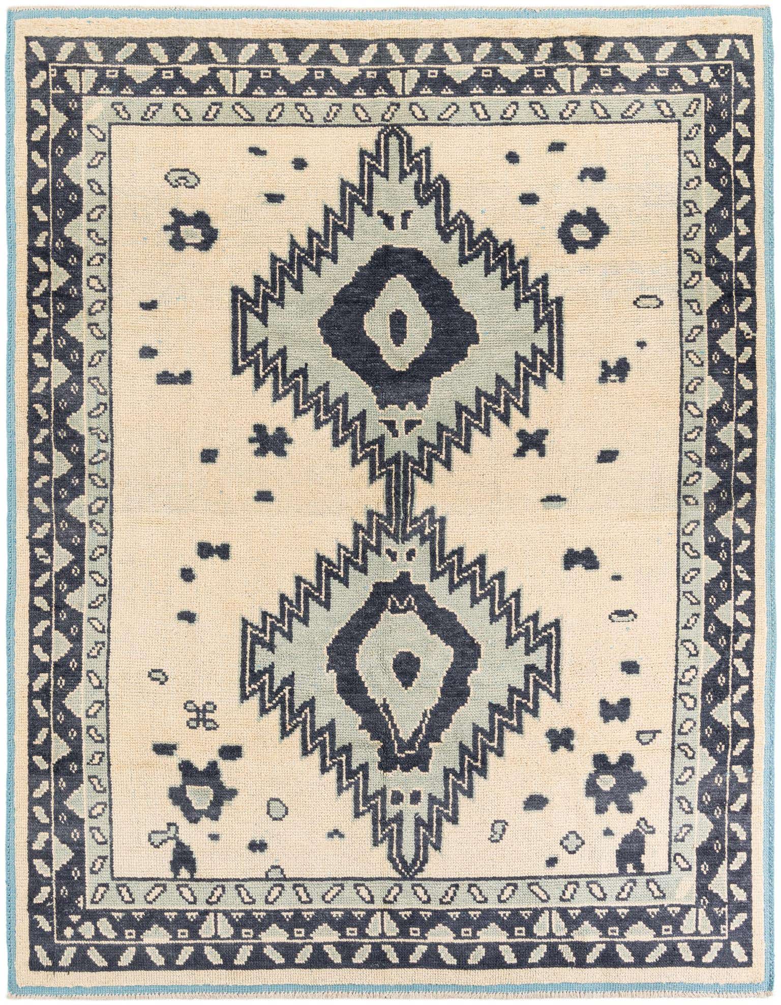 An 8x10 rectangular ivory wool shag rug with a central tribal medallion design in shades of blue and black, framed by a patterned border.