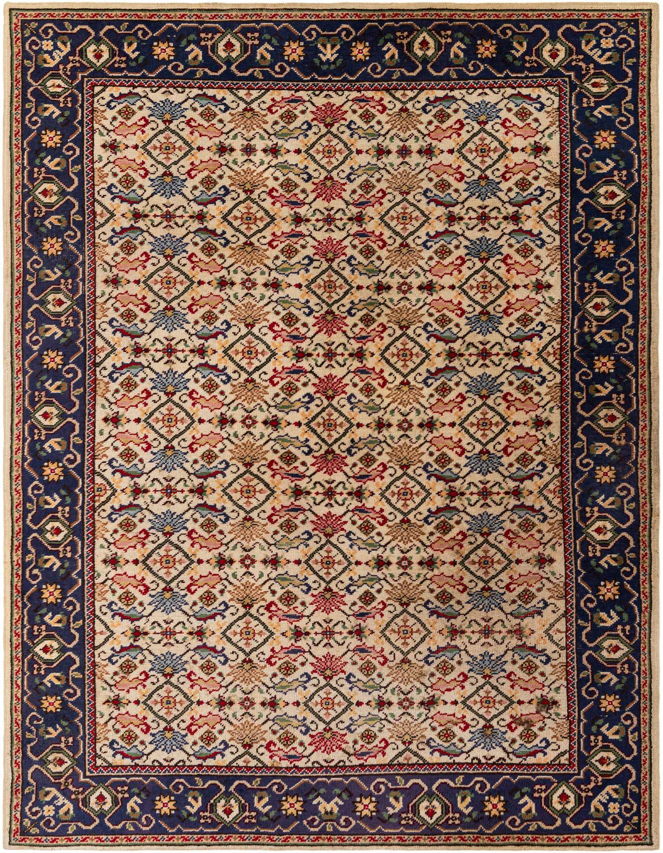A rectangular 6x9 ivory wool shag rug with a traditional tribal pattern and a dark blue border, suitable for a living room.