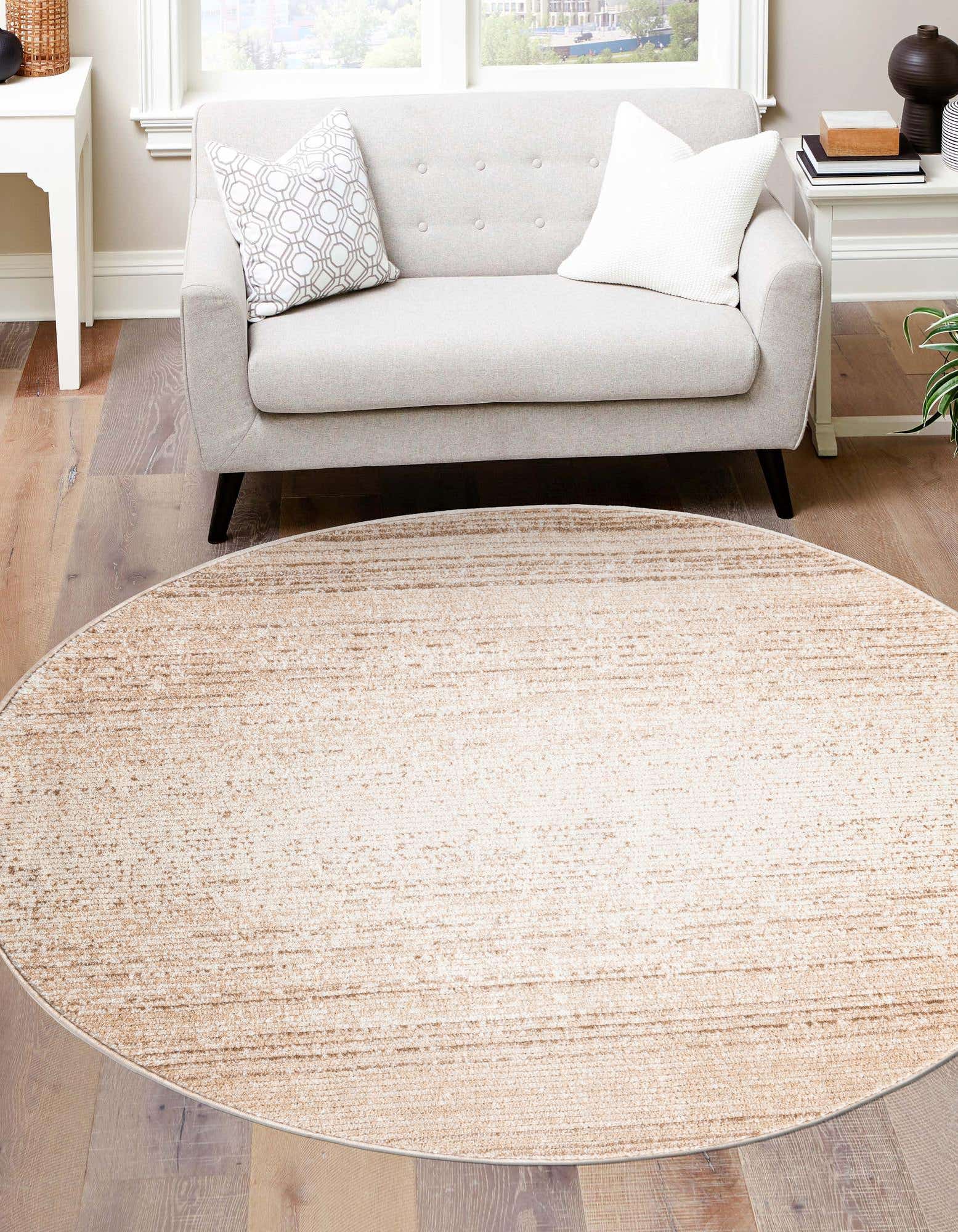 A 7' 10 round ivory and cream polypropylene rug with a subtle striped pattern on a hardwood floor in a living room.