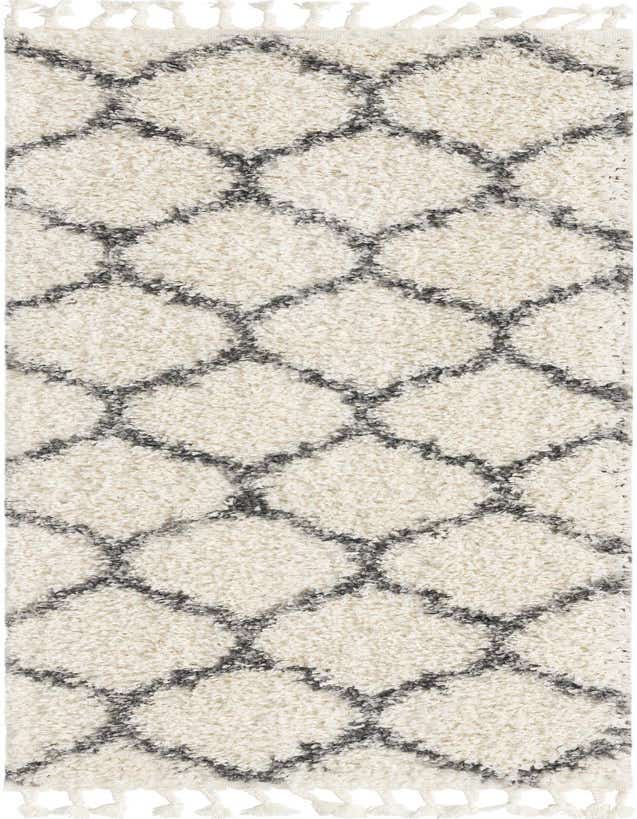 A close-up of an ivory shag runner rug featuring a charcoal gray geometric trellis pattern and decorative tassels.