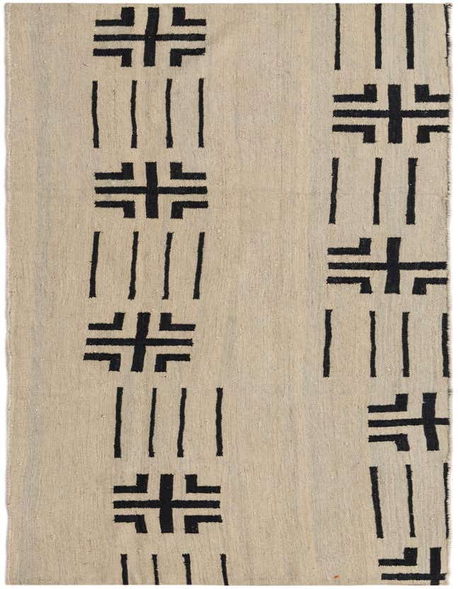 A 7 ft runner rug in ivory with a black tribal pattern, featuring abstract crosses and vertical lines.