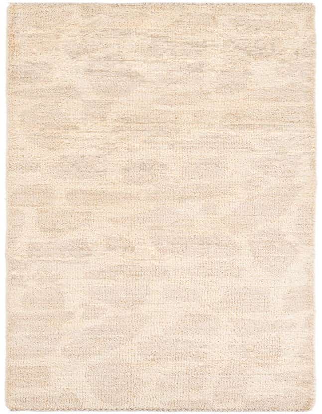 An 8 ft runner rug in ivory and cream, featuring a subtle tribal abstract pattern and plush shag pile.