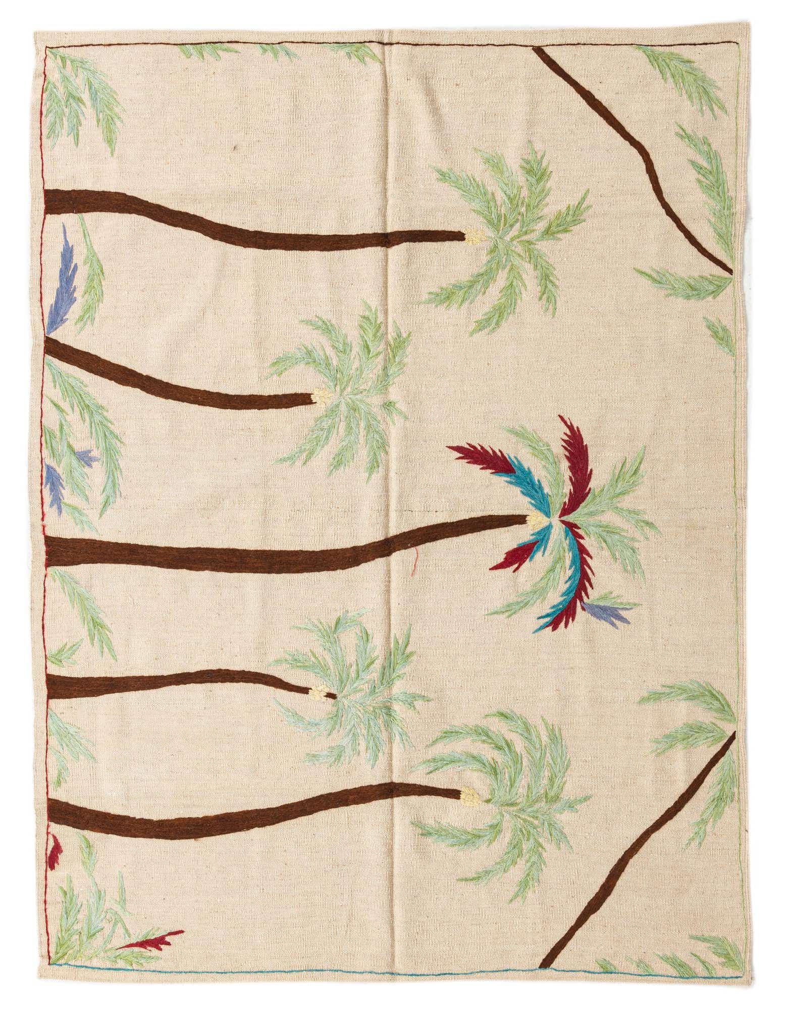 A square ivory wool rug featuring a vibrant, modern tribal pattern of palm trees with green, blue, and red fronds.