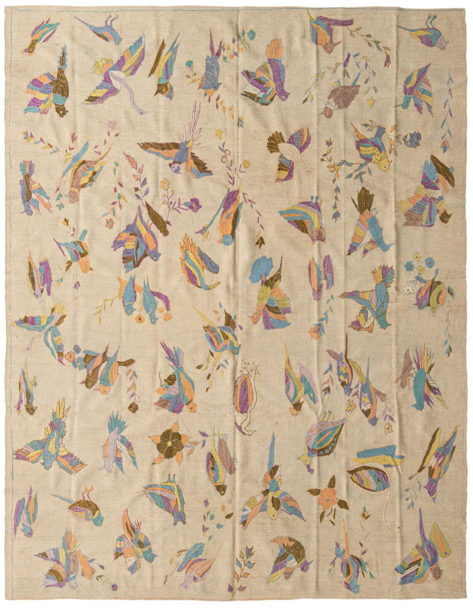 A square ivory flatweave rug with a vibrant, scattered tribal bird and floral pattern in blues, purples, oranges, and browns.