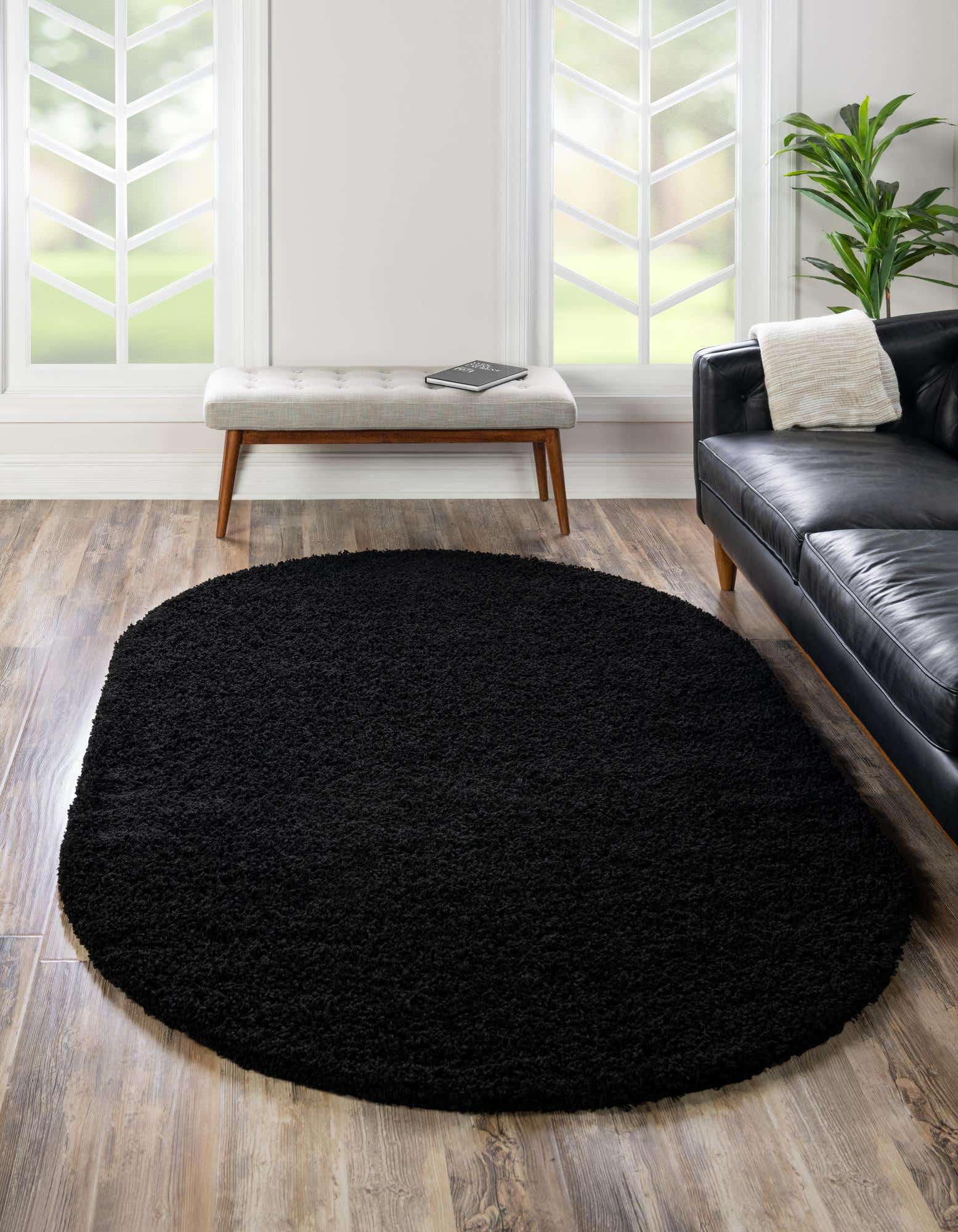 A plush, solid black oval shag rug, 7' 10 x 10' 0, offering soft texture for an indoor space.