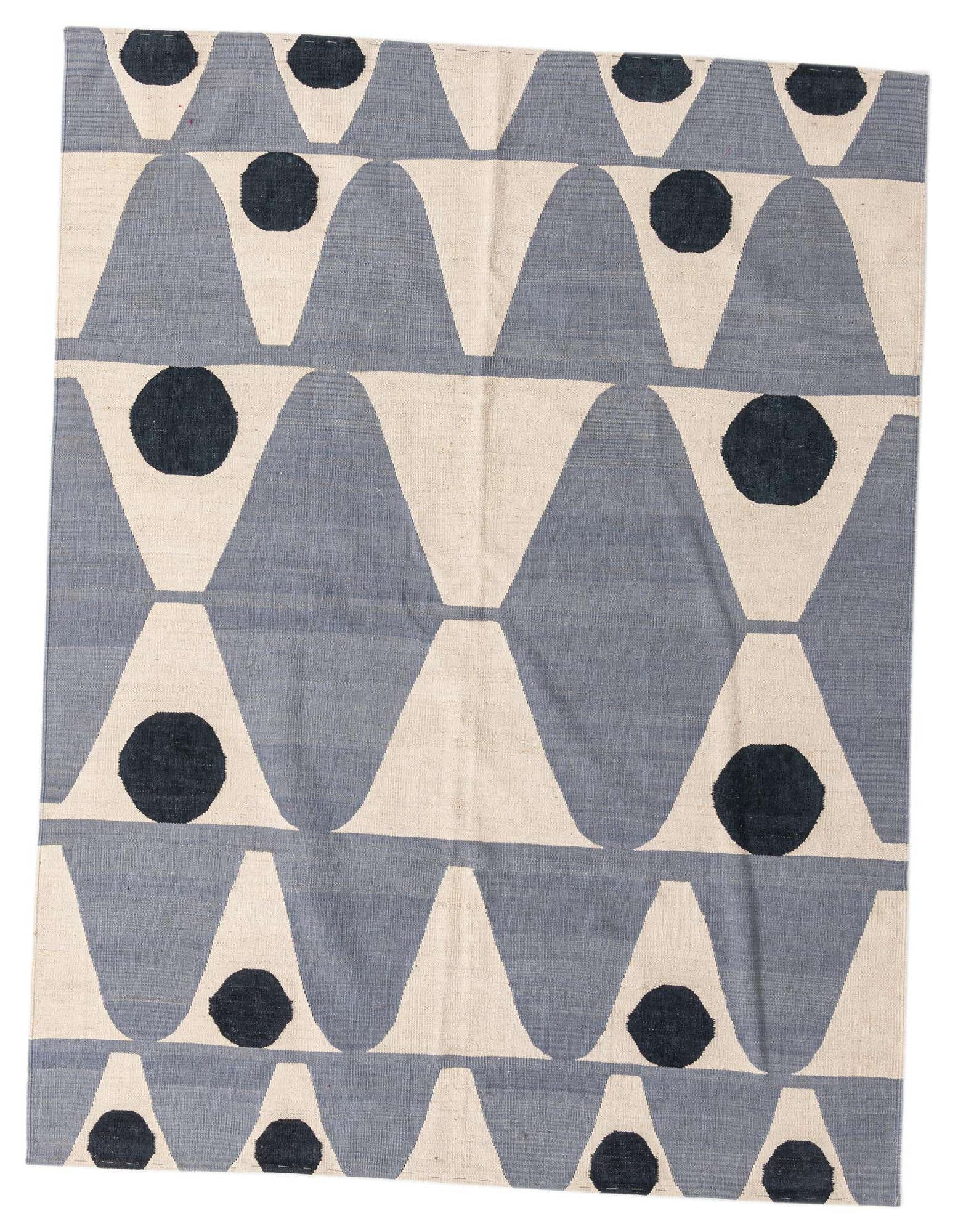 A 6x9 rectangular light blue and off-white flatweave rug with a modern tribal pattern of inverted U-shapes and dark blue circles.