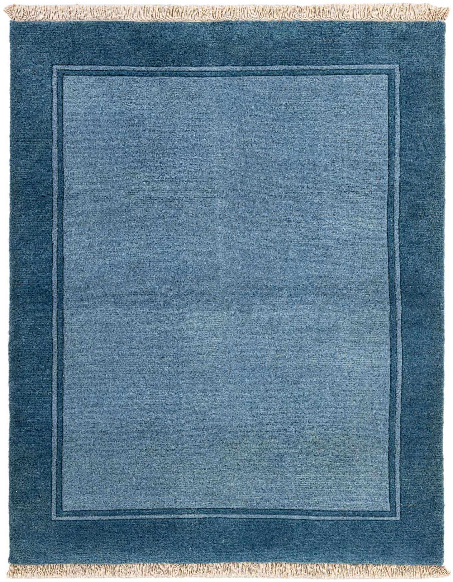 A 4x6 rectangular light blue wool area rug with a darker blue border, featuring short white fringes.