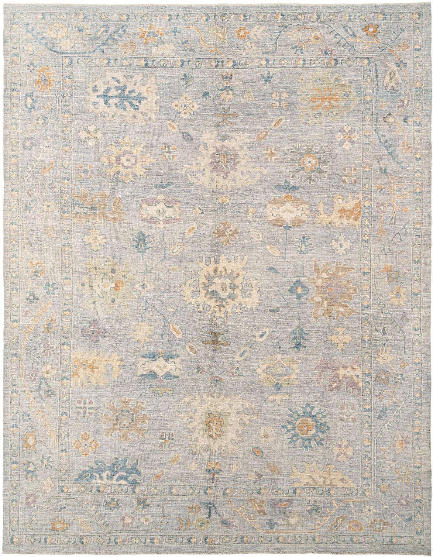 A rectangular handmade wool rug with a light blue background and a traditional Persian floral pattern in muted blues, creams, and oranges.