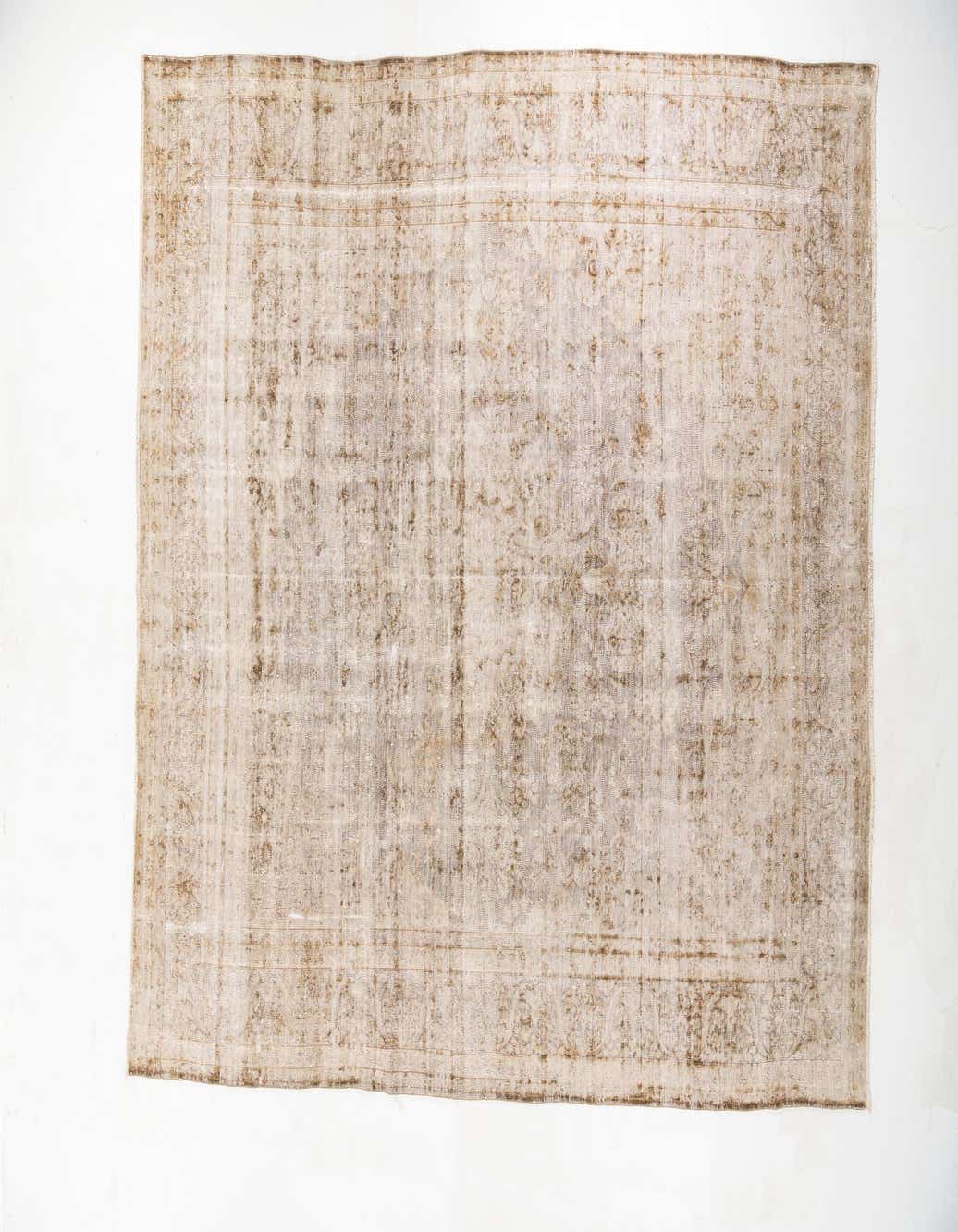 A 10x13 rectangular brown and tan wool rug with a faded vintage medallion and border pattern, suitable for a living room.