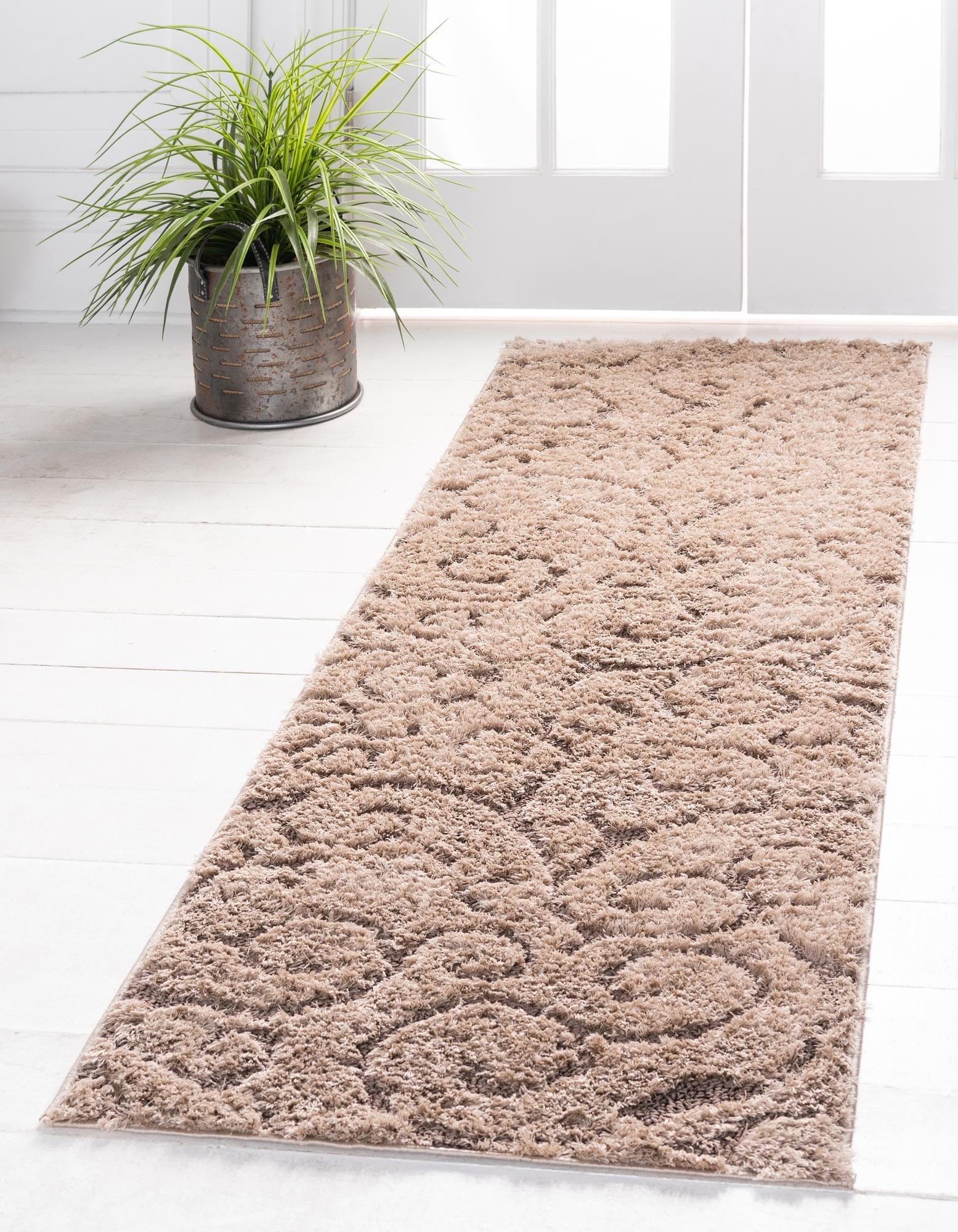 A 7 ft runner rug in shades of brown and tan, featuring a high/low textured pile with an abstract, transitional botanical pattern, ideal for a hallway.