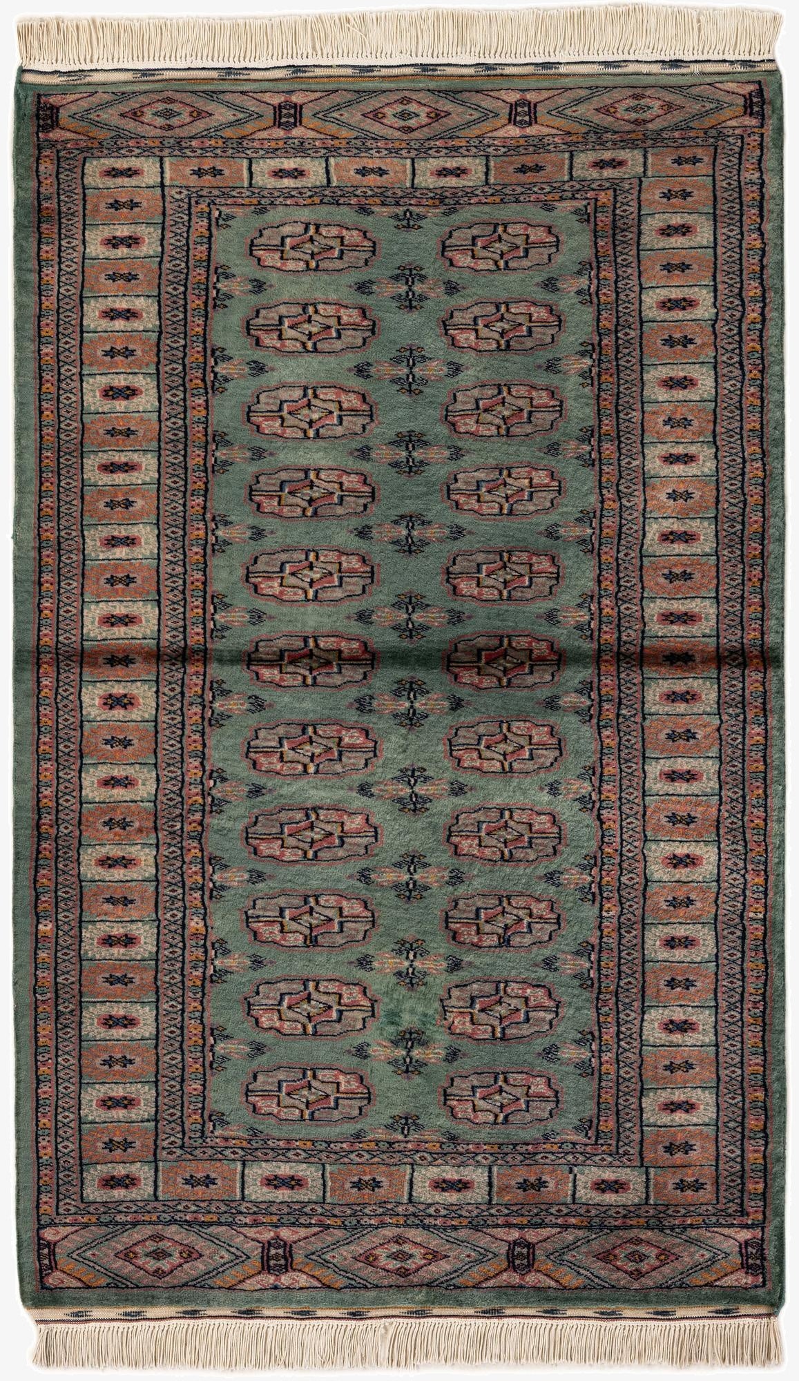 A 3x5 rectangular green Bokhara tribal rug with a shag pile, featuring intricate geometric patterns in muted reds, blues, and creams, and white fringed ends.