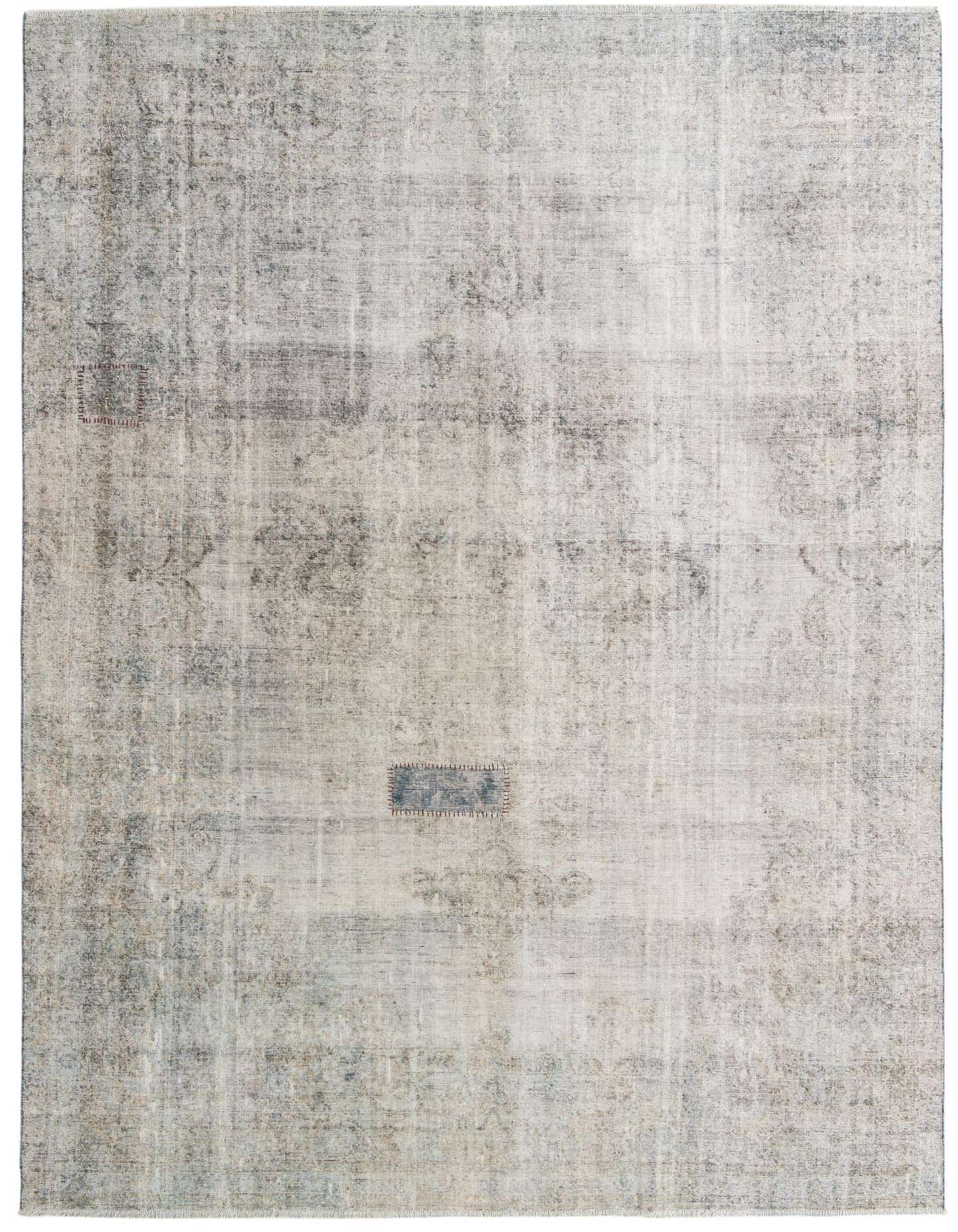 An 8x12 rectangular Ultra Vintage rug in faded greens and grays, featuring a distressed Persian-inspired pattern and a small blue patch.