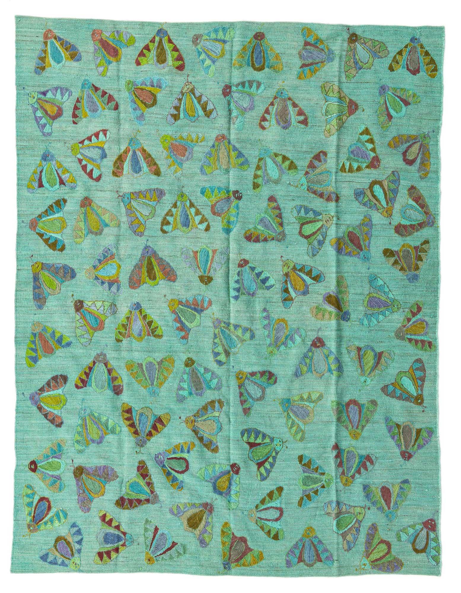 A square green Kilim Suzani rug featuring a vibrant, repeating pattern of colorful tribal moths or butterflies.