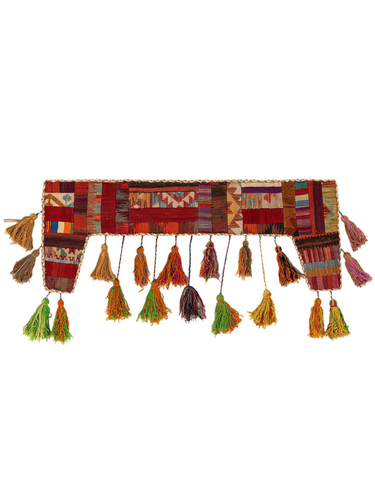 A vibrant, multi-colored rectangular wool wall hanging with abstract patterns and numerous colorful tassels along the bottom and sides.