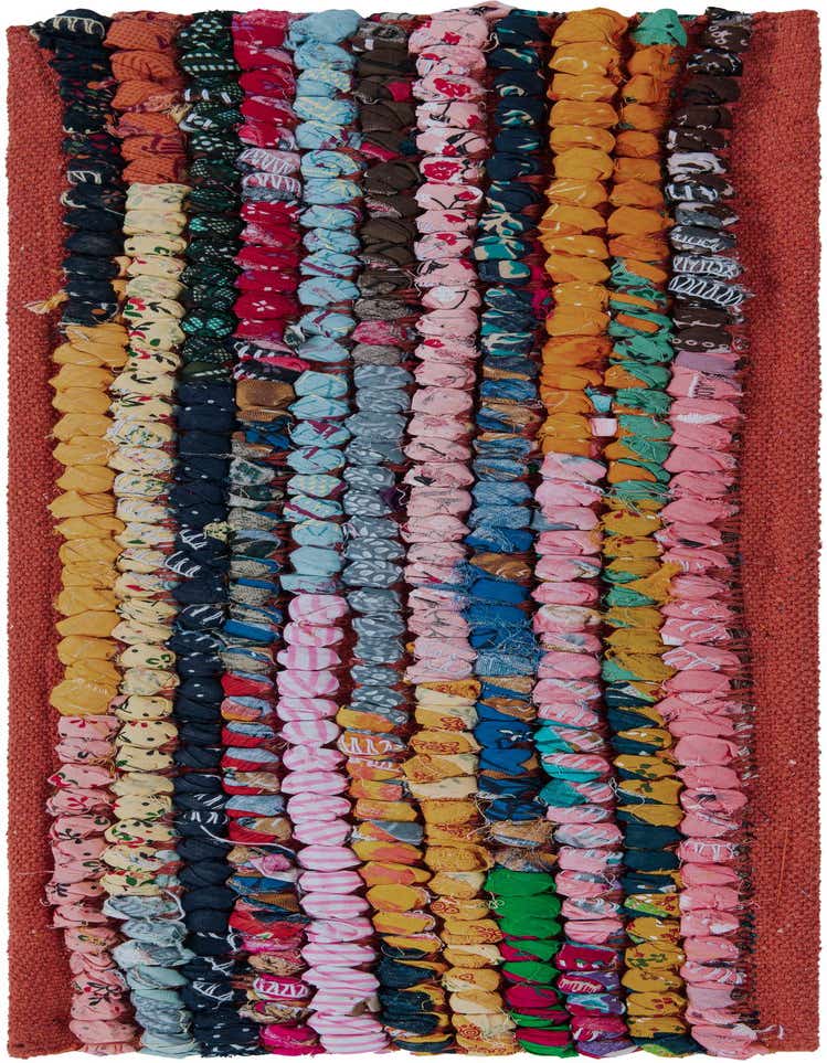 A close-up of a multi-colored Rugs.com Braided Chindi stair rug, featuring rows of vibrant, textured cotton braids in various patterns and hues, with an orange border.
