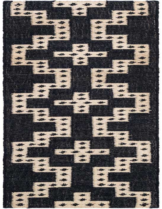 A close-up of an 8 ft runner rug with a modern tribal pattern in deep blue and off-white, featuring small black star-like accents.