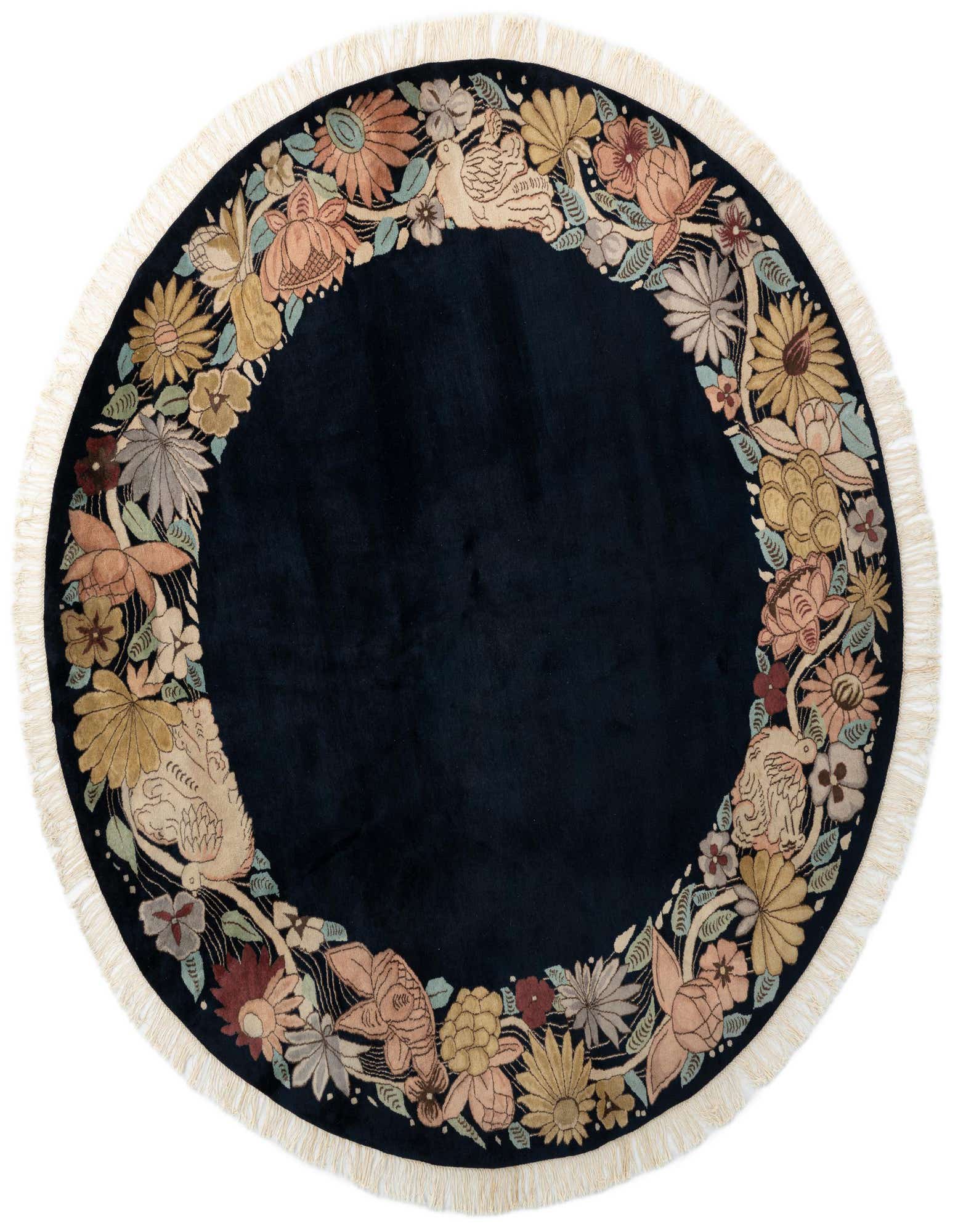 A round navy blue wool rug with a vibrant border of colorful floral and bird patterns, featuring cream fringe.