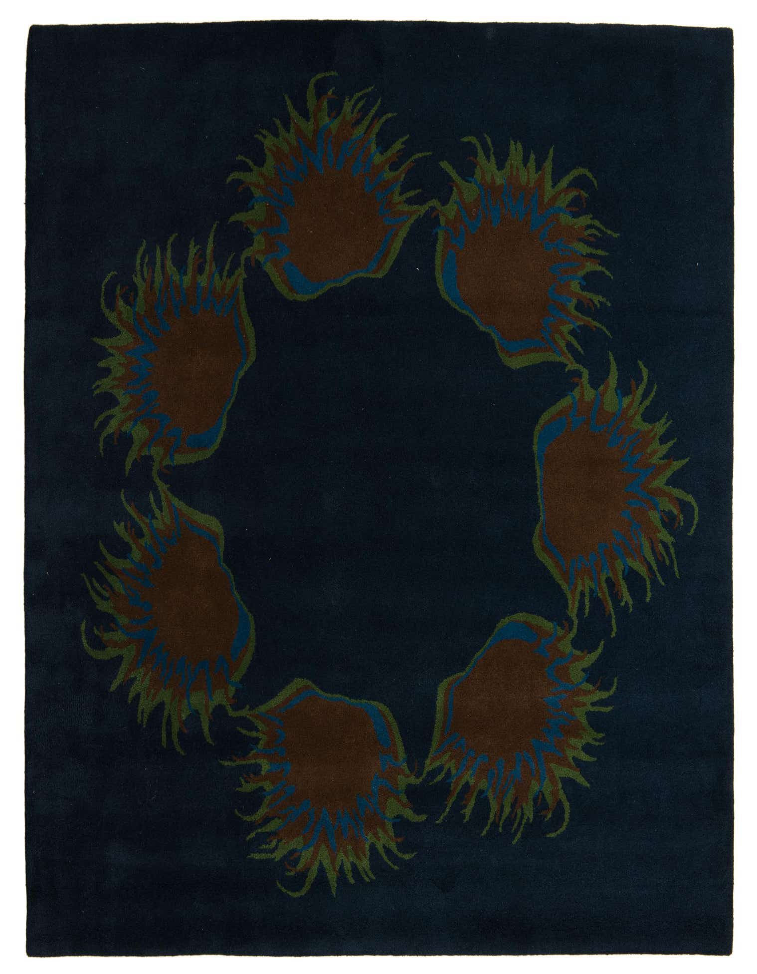 A square navy blue rug with a modern design featuring a circular arrangement of six brown, blue, and green spiky abstract shapes.