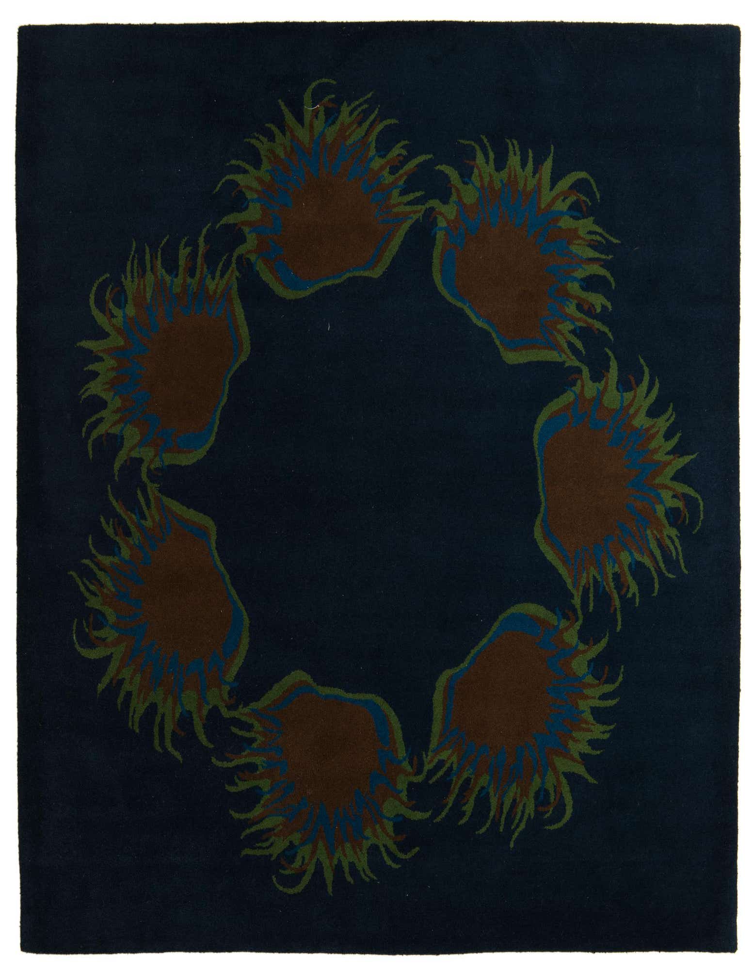 A square navy blue rug with a circular modern pattern of six abstract brown, green, and blue sun-like shapes.