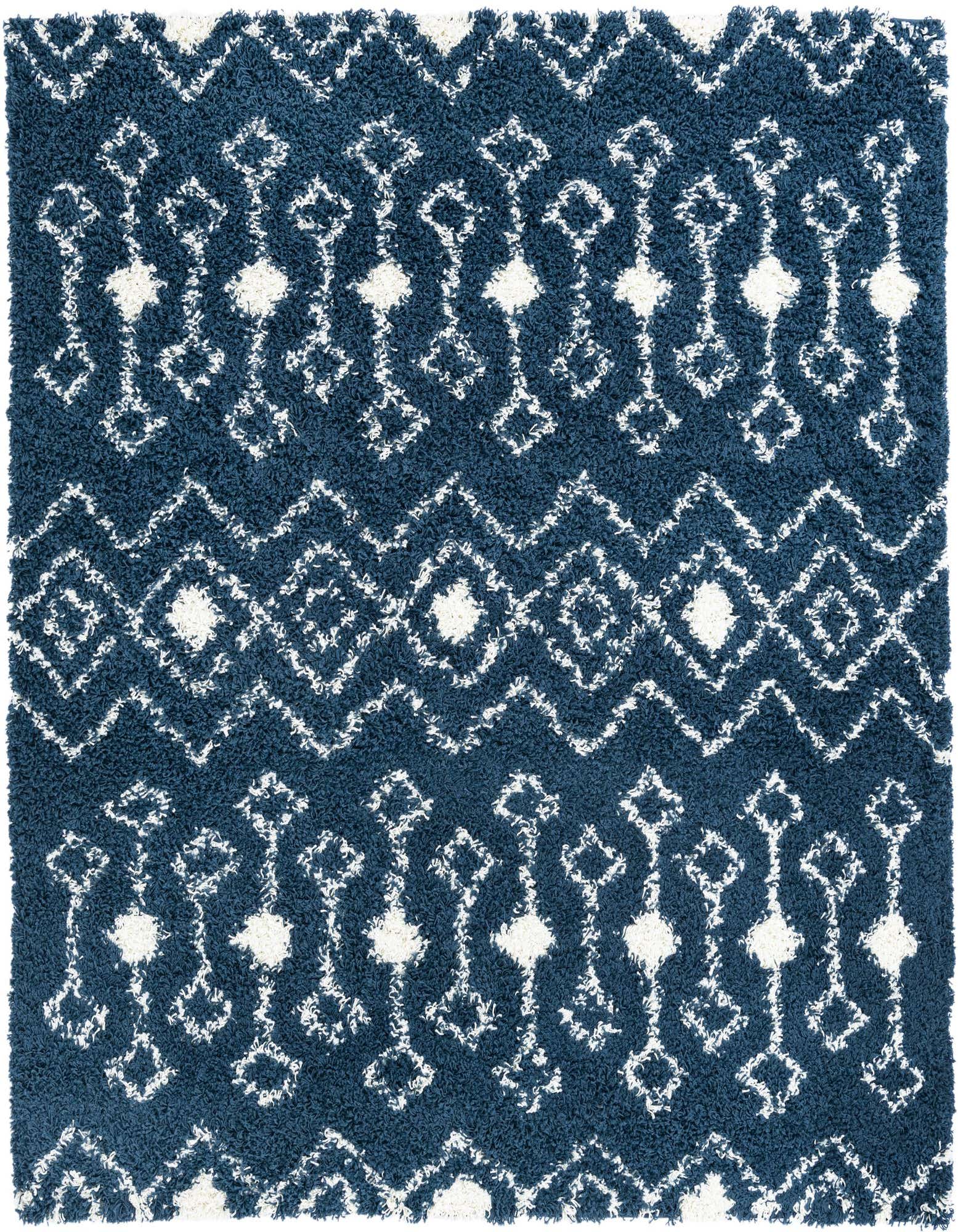 A square navy blue shag rug with a white modern tribal pattern, featuring diamond and zigzag motifs.
