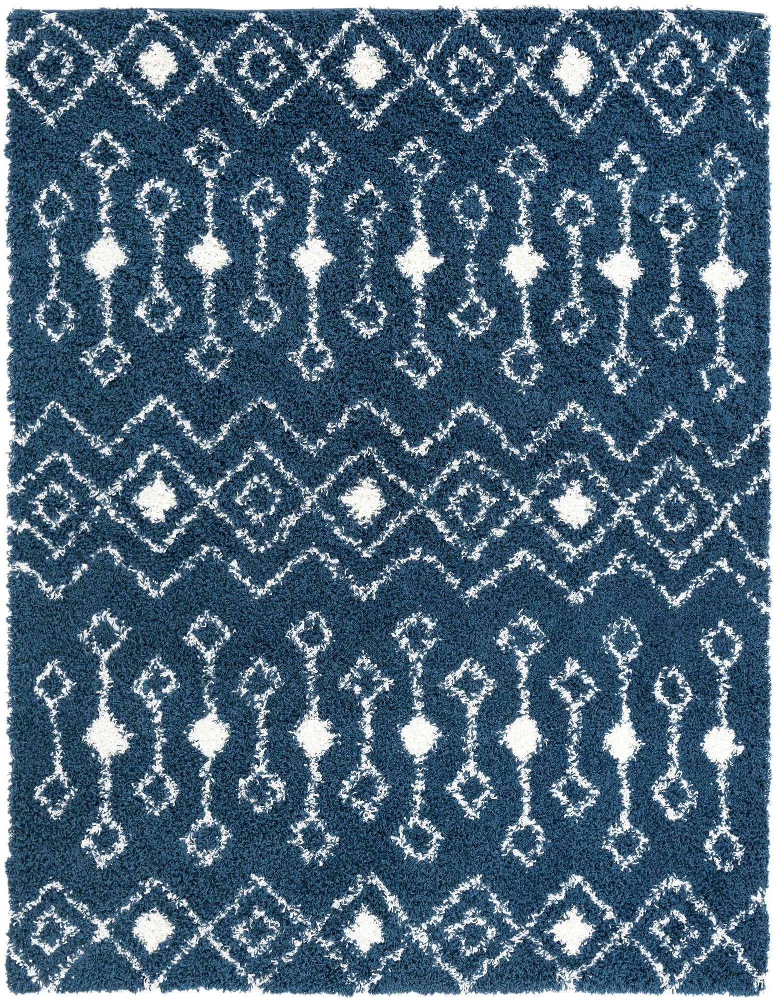 A square navy blue shag rug with a white tribal pattern featuring diamonds and abstract geometric shapes.
