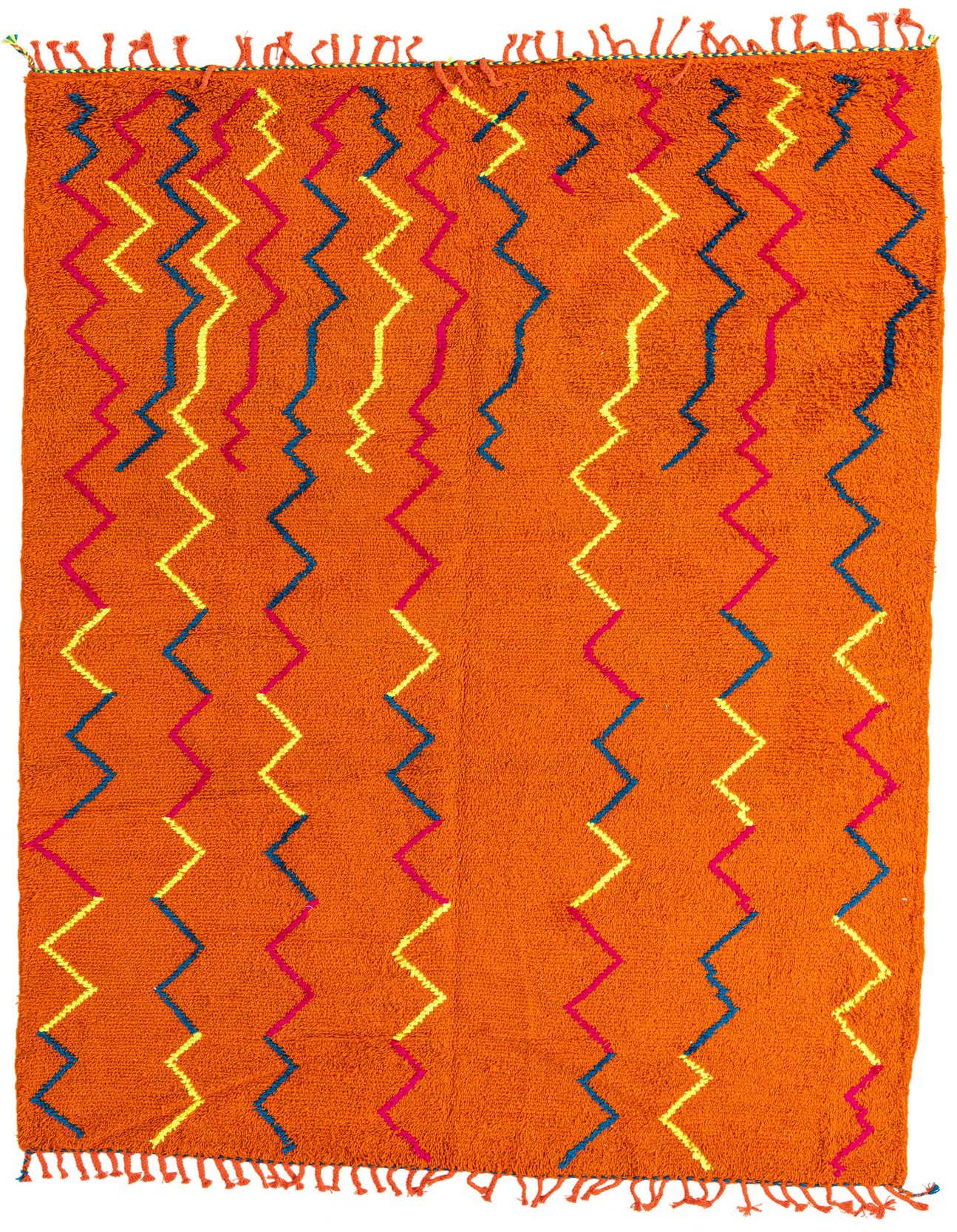 A 7x10 rectangular orange shag rug with vibrant blue, yellow, and pink zigzag tribal patterns, featuring short fringe.