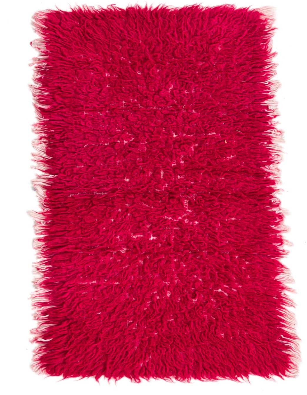 A vibrant 2x3 rectangular pink shag rug with a tribal pattern and fringed edges, made of wool.