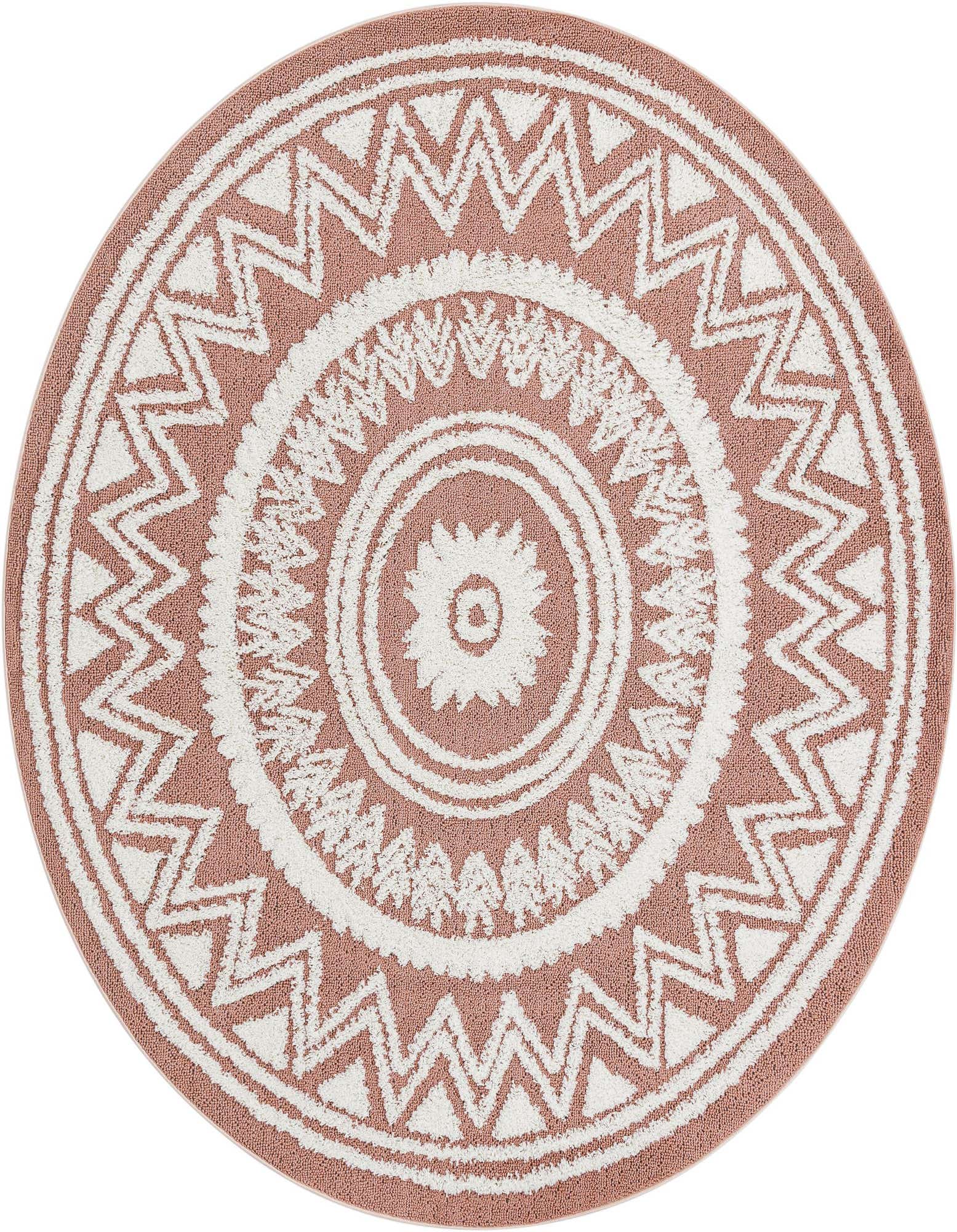 A round pink and white rug featuring a Southwestern-inspired medallion pattern with tribal zigzags and a central floral motif.