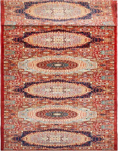 A long, rectangular Amina Persian wool runner rug in rich reds, blues, and creams, featuring intricate traditional patterns.