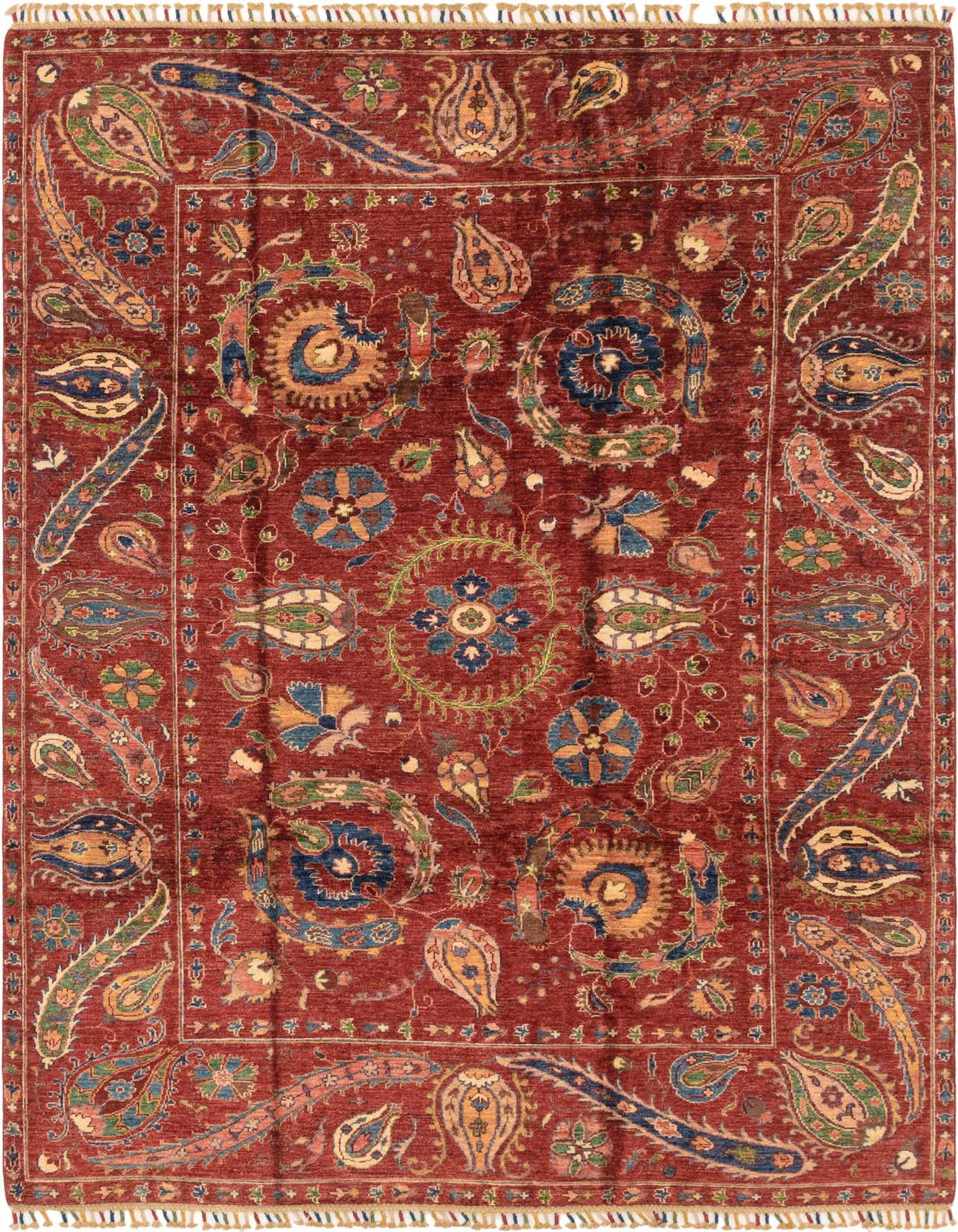 A 6x9 rectangular Ariana Ziegler rug featuring a traditional tribal pattern with intricate floral and paisley motifs in shades of blue, green, and gold on a rich red background, with visible fringe.