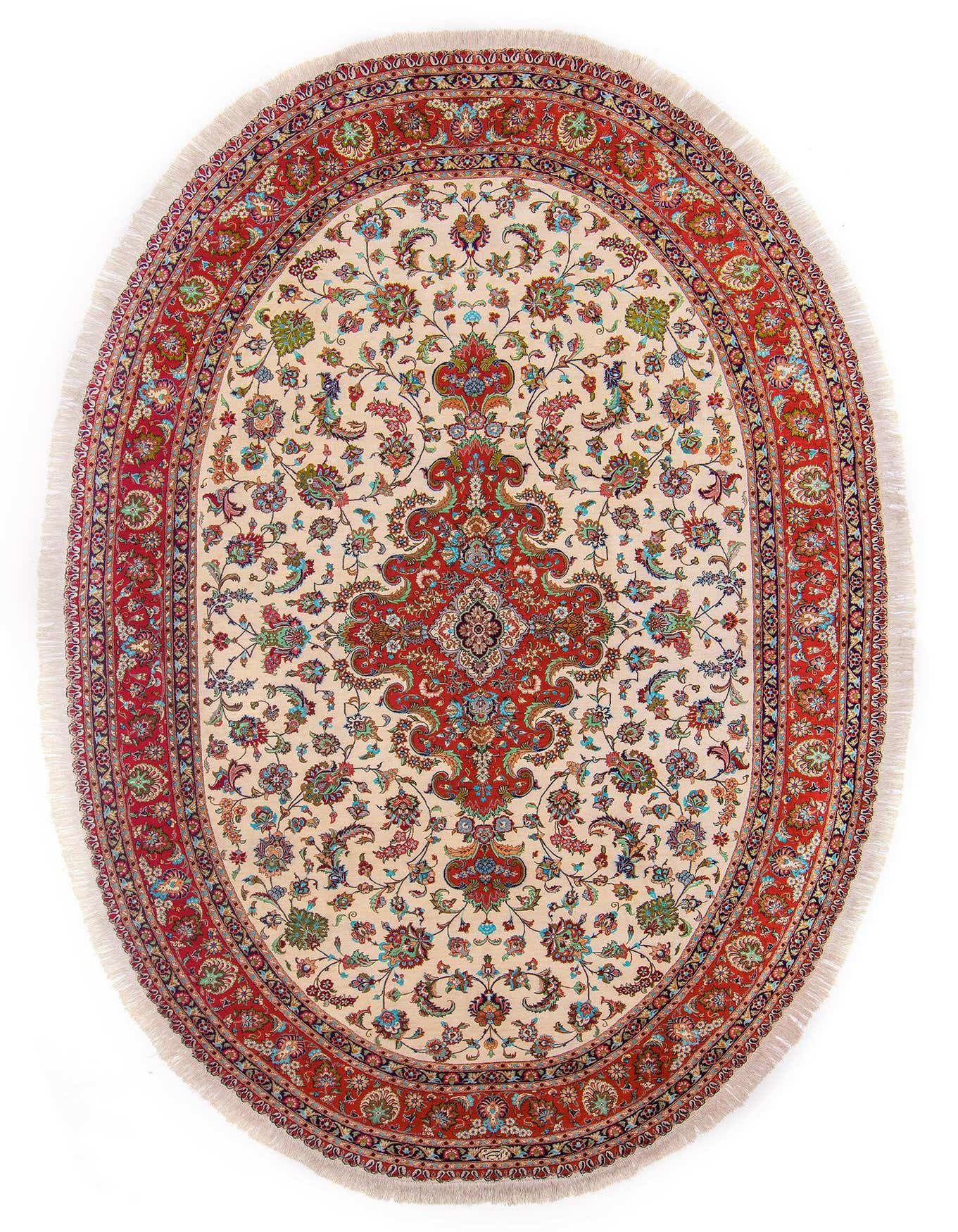 A 7x10 rectangular Ghom Persian rug with a cream field, a large red central medallion, and an ornate red border with intricate floral patterns.
