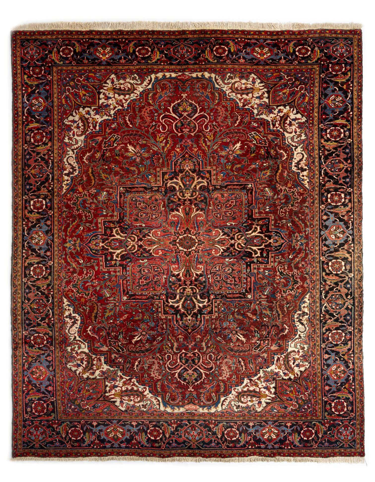 A 10x13 rectangular Heriz Persian rug with a rich red field, intricate floral patterns, and a dark border, suitable for a living room.