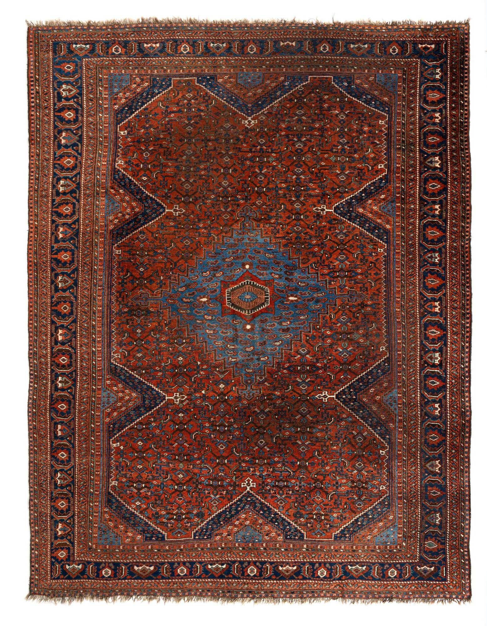 A rectangular 8x11 handmade Persian rug with a rich red field and intricate blue geometric patterns, suitable for a living room.