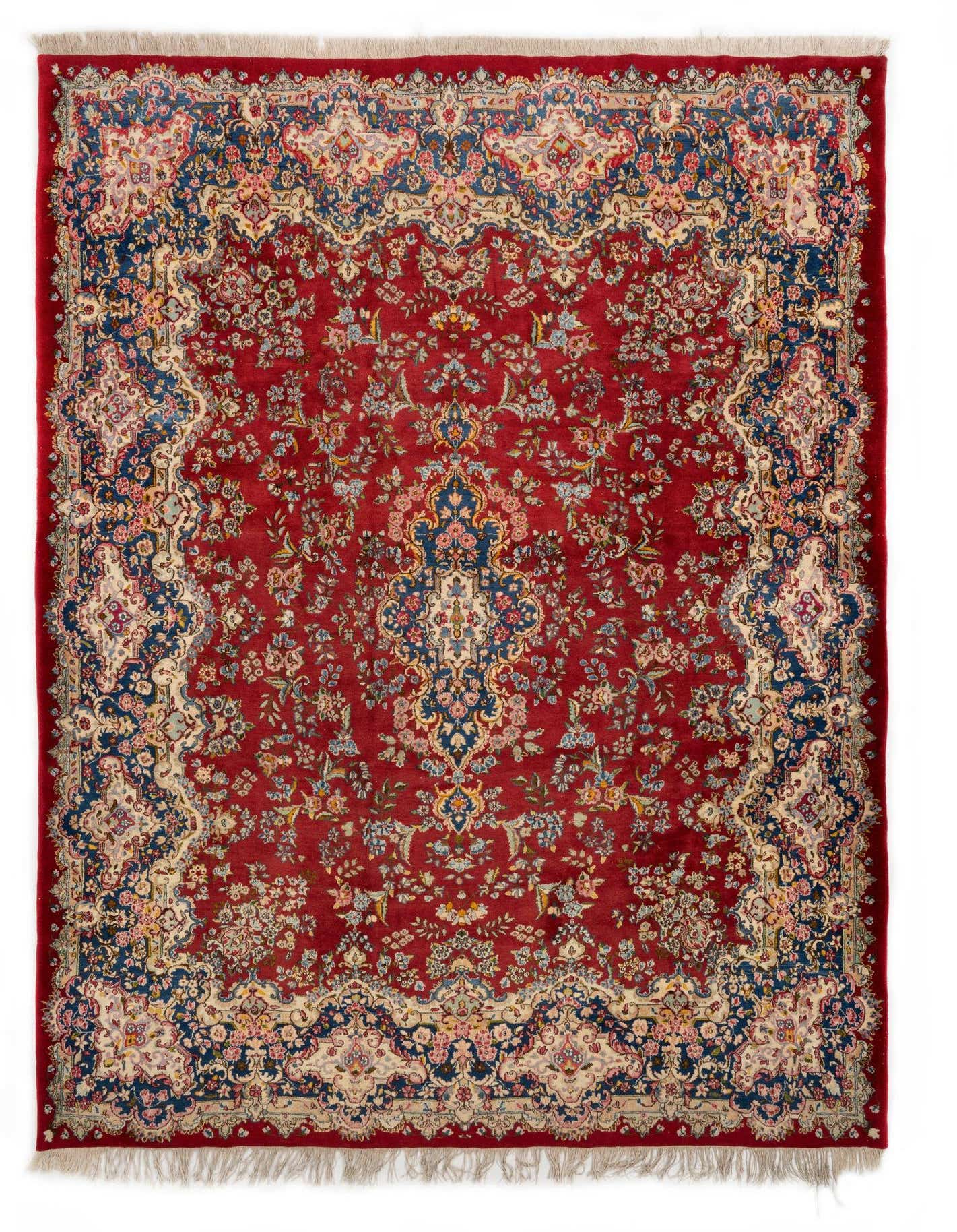 An 8x11 rectangular Kerman Persian rug in rich red, featuring an ornate floral and medallion pattern with navy blue and cream accents.