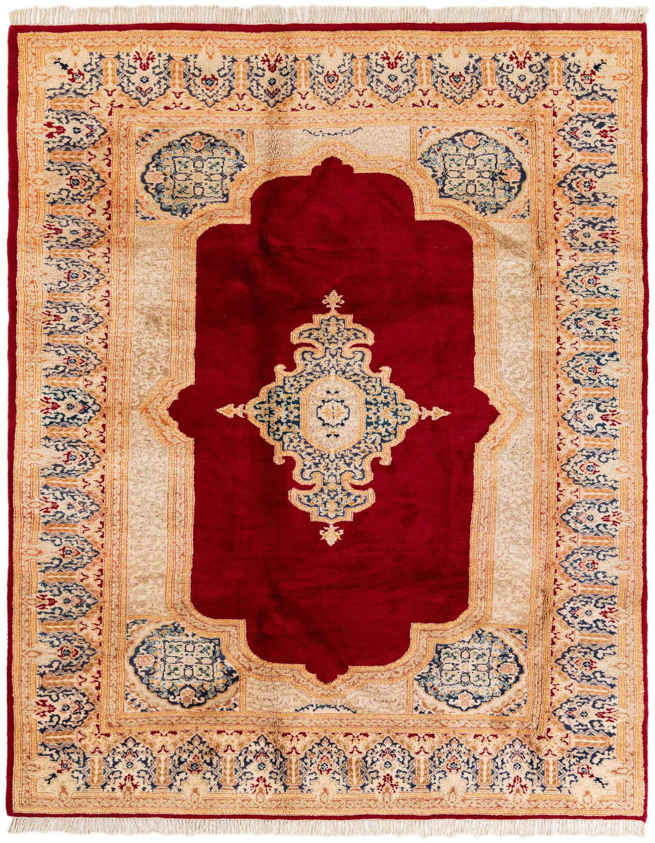 A 6x9 rectangular Kerman wool rug with a deep red field and an ornate cream, blue, and gold medallion and border.